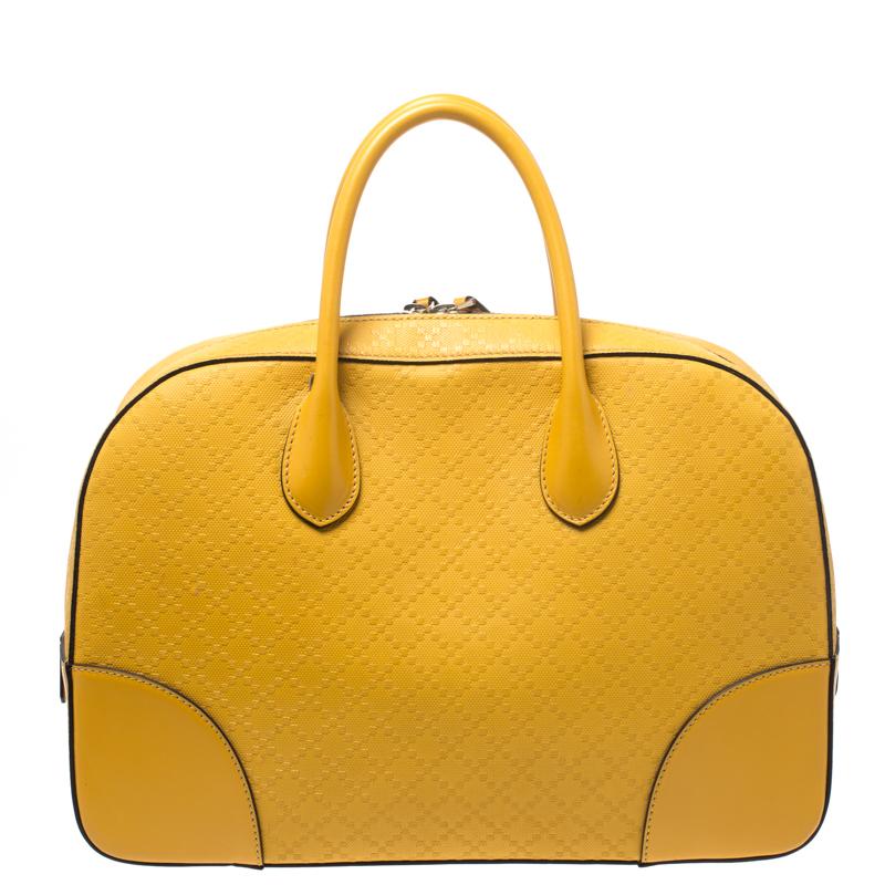 This Gucci satchel is crafted from bright yellow Diamante leather with smooth trims into a structured silhouette. The bag features dual handles and protective metal feet at the bottom. The top zip closure opens to a canvas-lined interior that houses