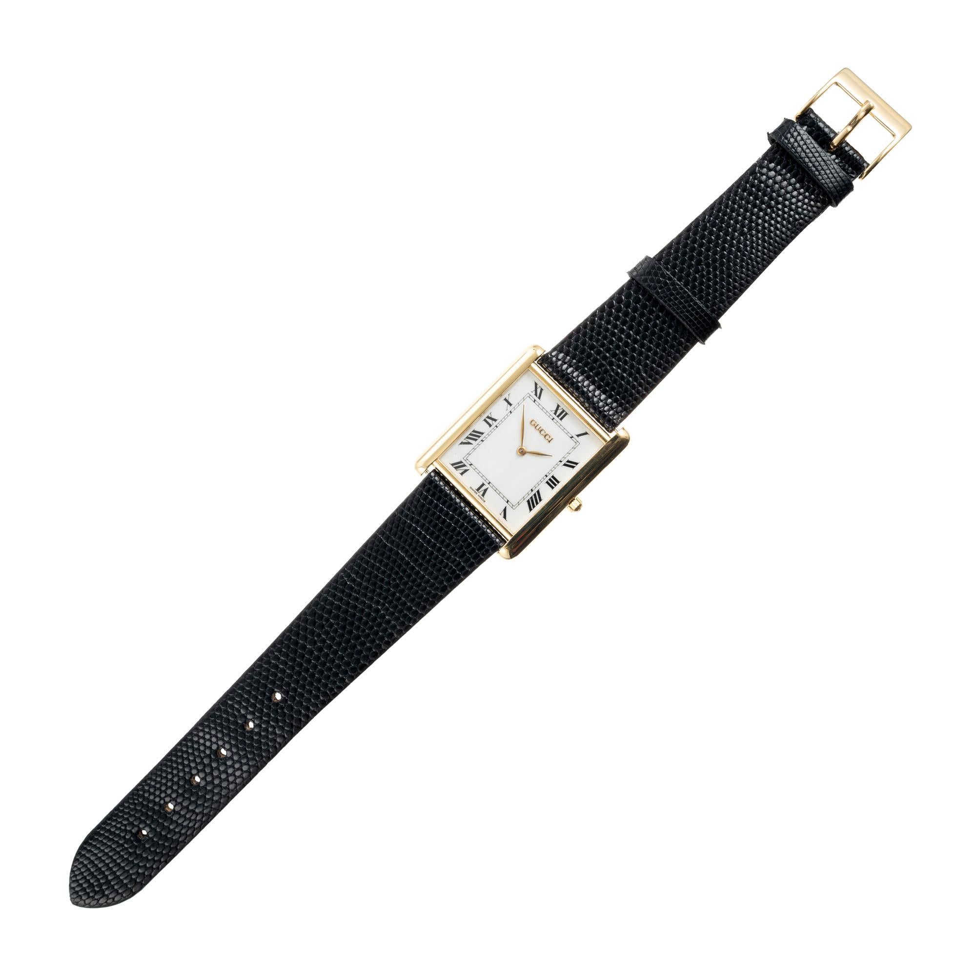 Mens tank style 18k yellow gold wristwatch. Original Gucci quartz watch with white dial and Roman numerals. 

Length: 35.17mm
Width: 28mm
Band width at case: 20mm
Case thickness: 5.35mm
Band: Black genuine lizard
Crystal: sapphire
Dial: white with