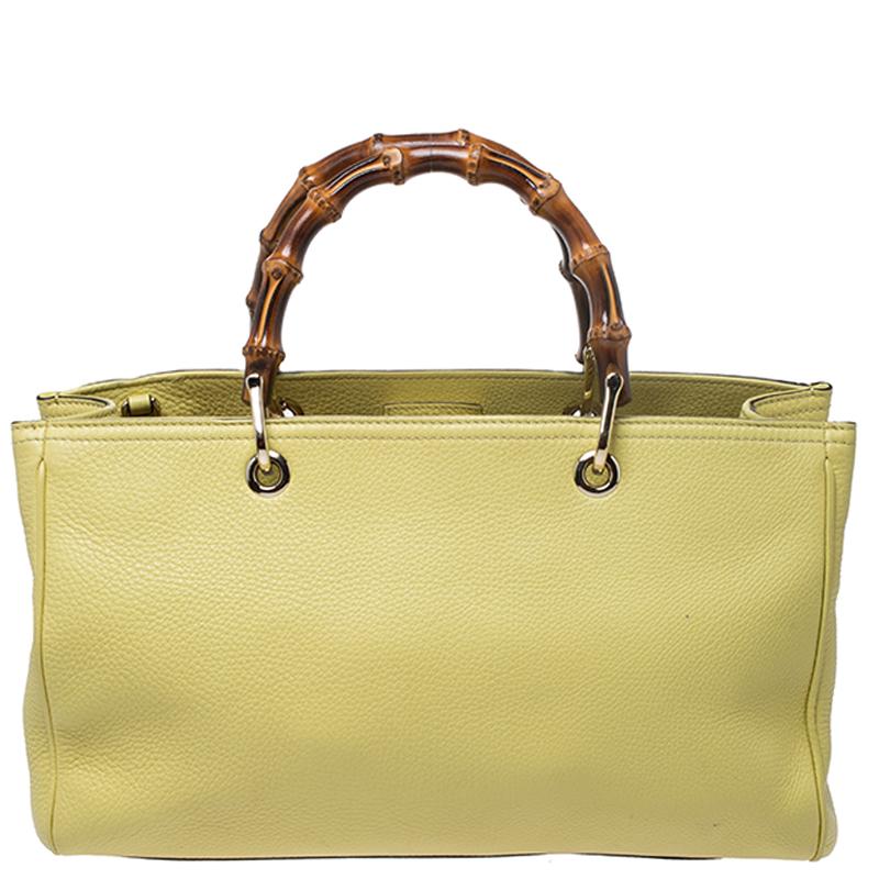 This elegant tote from Gucci is crafted to a standard of perfection. The yellow color tote comes with a detachable shoulder strap and bamboo top handles. The magnetic snap closure opens to a fabric lined interior with two compartments for you to