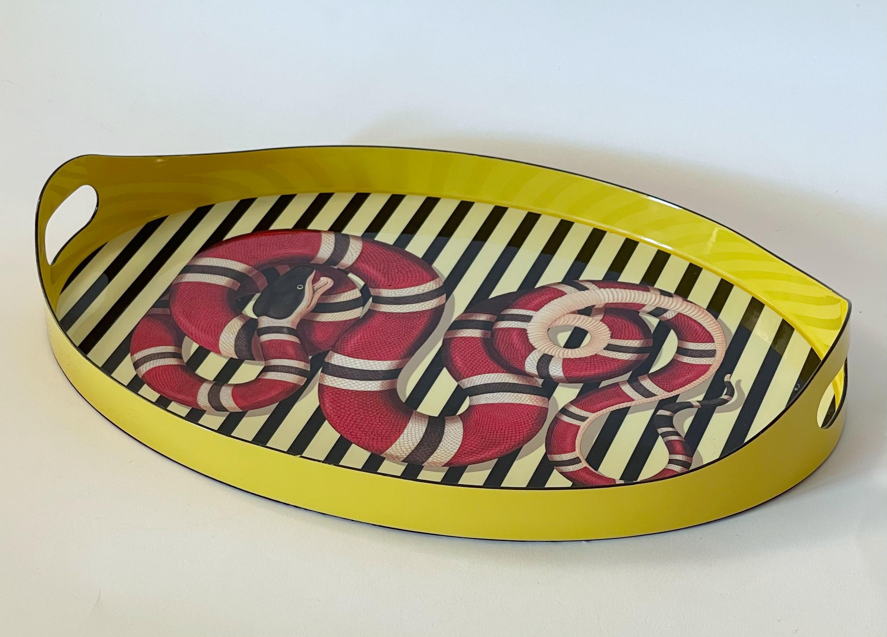 Bandeja ovalada de metal esmaltado amarillo, rojo y negro GUCCI con motivos de serpiente rey y franja en el centro, asas dobles a los lados / Made in Italy
Sello original en la parte inferior / viene en su caja original
Anchura: 16 pulgadas /
