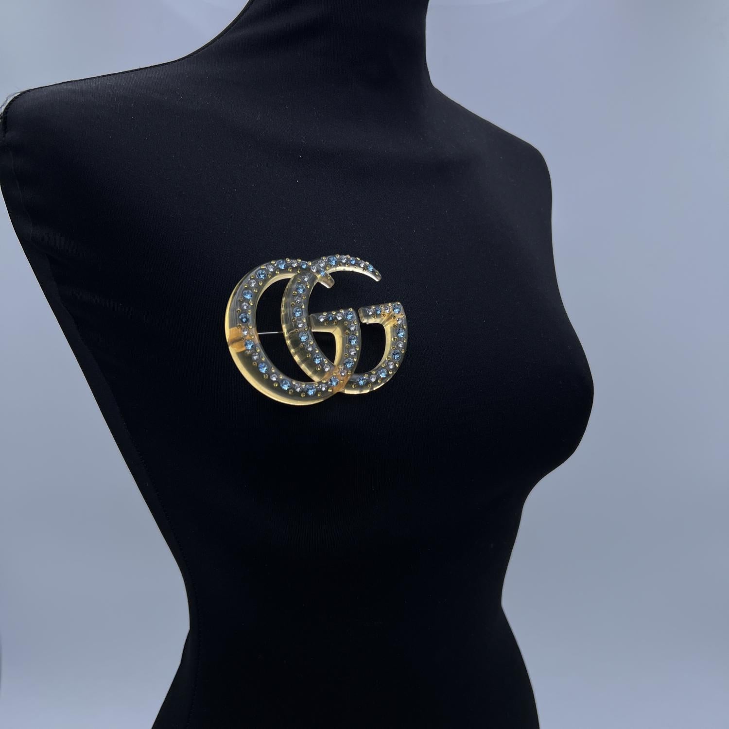 Beautiful Gucci clear yellow GG Marmont Brooch in resin. White and light blue crystals embellishment. Safety pin closure on the back. Approx. width: 3.25 inches - 8.2 cm. Approx. height: 2.5 inches - 6.3 cm. Signed 'Gucci - made in Italy' on the