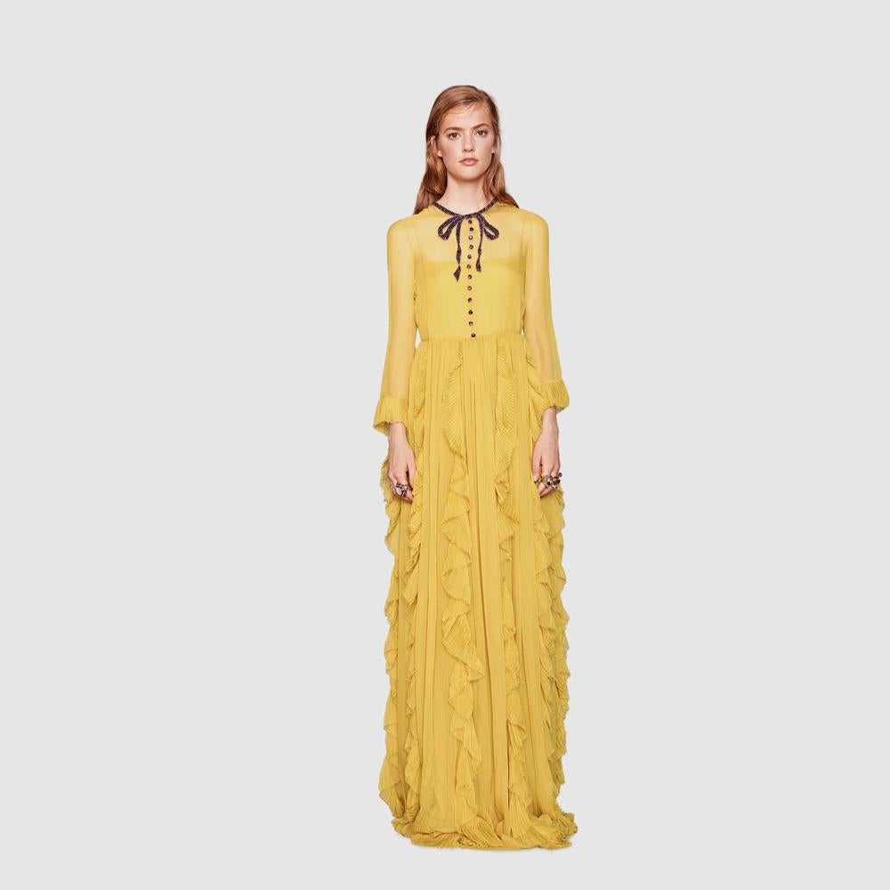 A silk chiffon gown with plissé ruffles and an embroidered bow and button neckline. Violet and amethyst crystal handmade embroidered bow patches and button embroidery.
Oil yellow silk chiffon.
Plissé ruffles.
Cropped sleeves.
Back keyhole