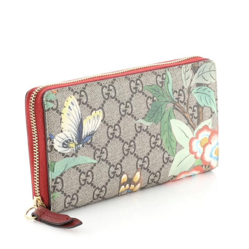 This Gucci Zip Around Wallet Tian Print GG Coated Canvas, crafted from brown printed GG coated canvas, features gold-tone hardware. Its zip-around closure opens to a red leather and brown fabric interior with multiple card slots and zip and slip