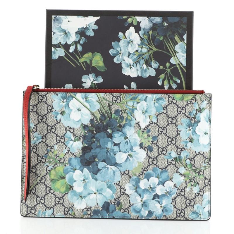 This Gucci Zipped Pouch Blooms Print GG Coated Canvas Large, crafted from GG supreme coated canvas with blooms print overlay and red suede,  features leather zip pulls and gold-tone hardware. Its zip closure opens to a neutral microfiber interior