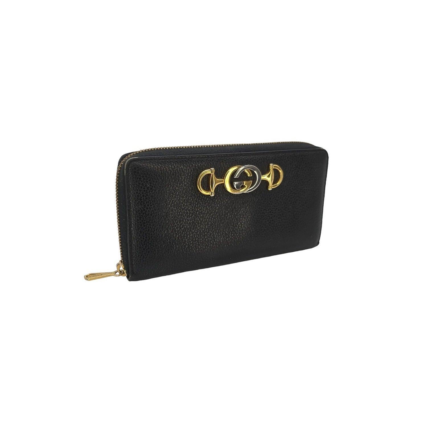 Expertly crafted from smooth calfskin leather, the Gucci Zumi Black Zip Around Wallet is a sleek and sophisticated accessory. The front flap is adorned with the iconic Gucci GG horsebit and opens to reveal a spacious interior with card slots, patch