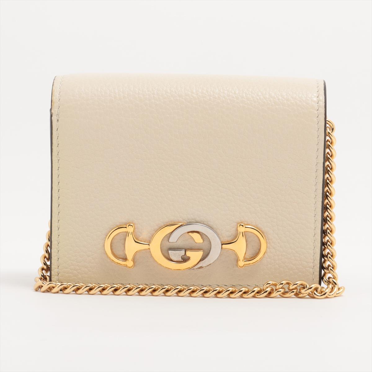 The Gucci Zumi Leather Chain Wallet in Ivory is a sophisticated and versatile accessory that blends classic elegance with modern functionality. Crafted from luxurious ivory leather, the wallet features the signature Interlocking G and Horsebit