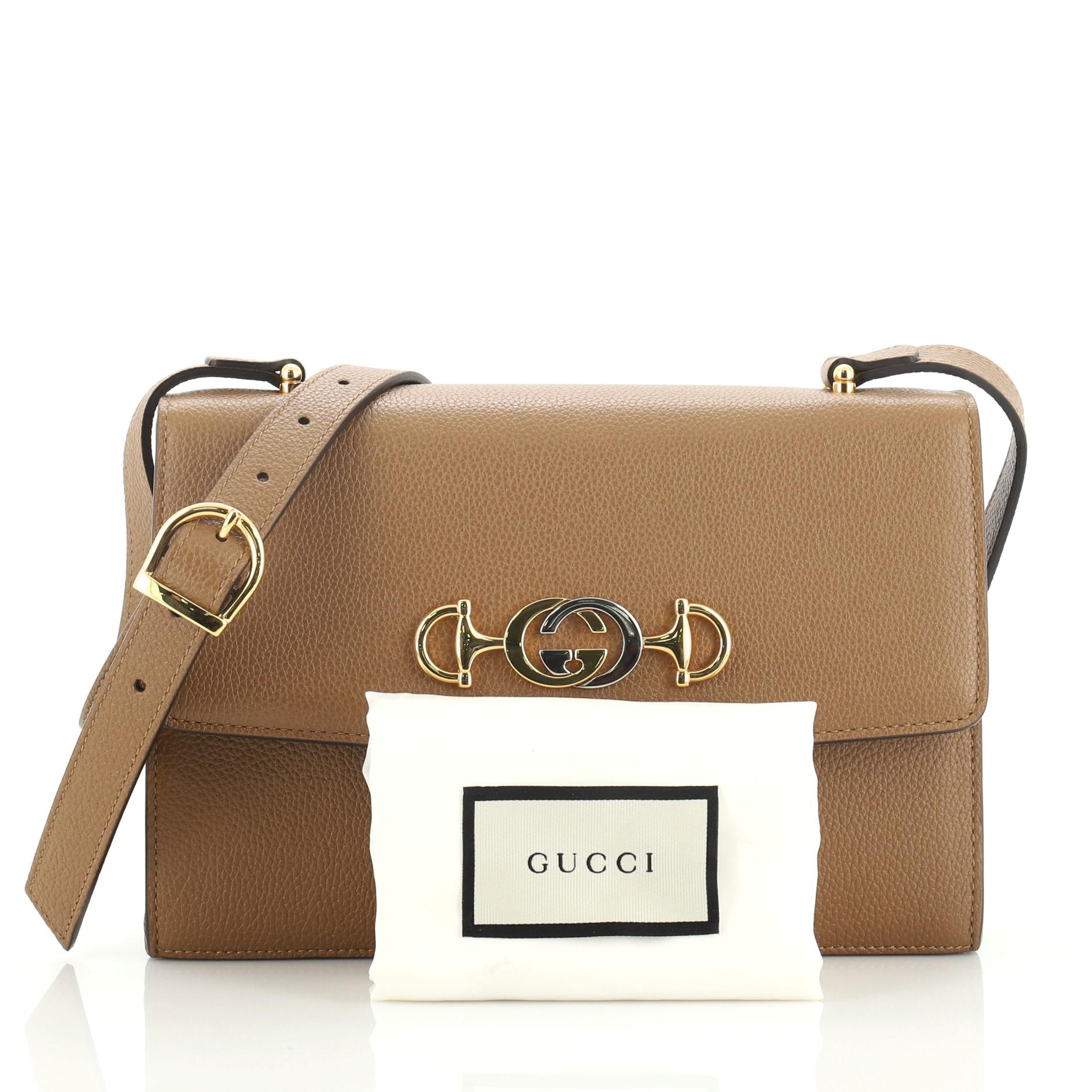 This Gucci Zumi Shoulder Bag Leather Small, crafted in brown leather, features adjustable leather strap, interlocking G Horsebit, and gold and silver-tone hardware. Its push lock closure opens to a gray fabric interior with slip pockets.

Condition: