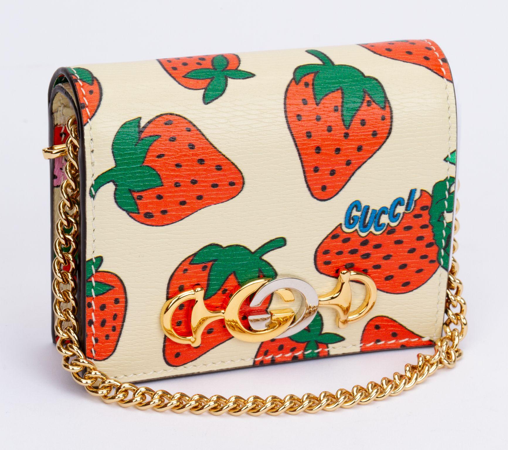 Gucci grained leather bifold shoulder bag in off-white featuring a strawberry graphic. Detachable curb chain wristlet drop (4.5