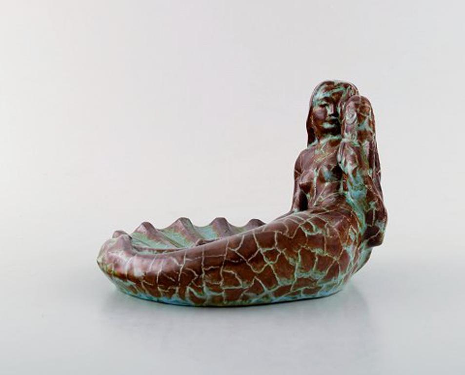 Gudmundur Mar Einarsson b. Middal 1895, 1963. Icelandic artist.
Sculpture / bowl in the form of lying mermaid with fish. Beautiful glaze in red, brown and turquoise tones, 1940s.
Signed in monogram. Iceland.
Measures: 19.5 x 13.5 cm
In perfect