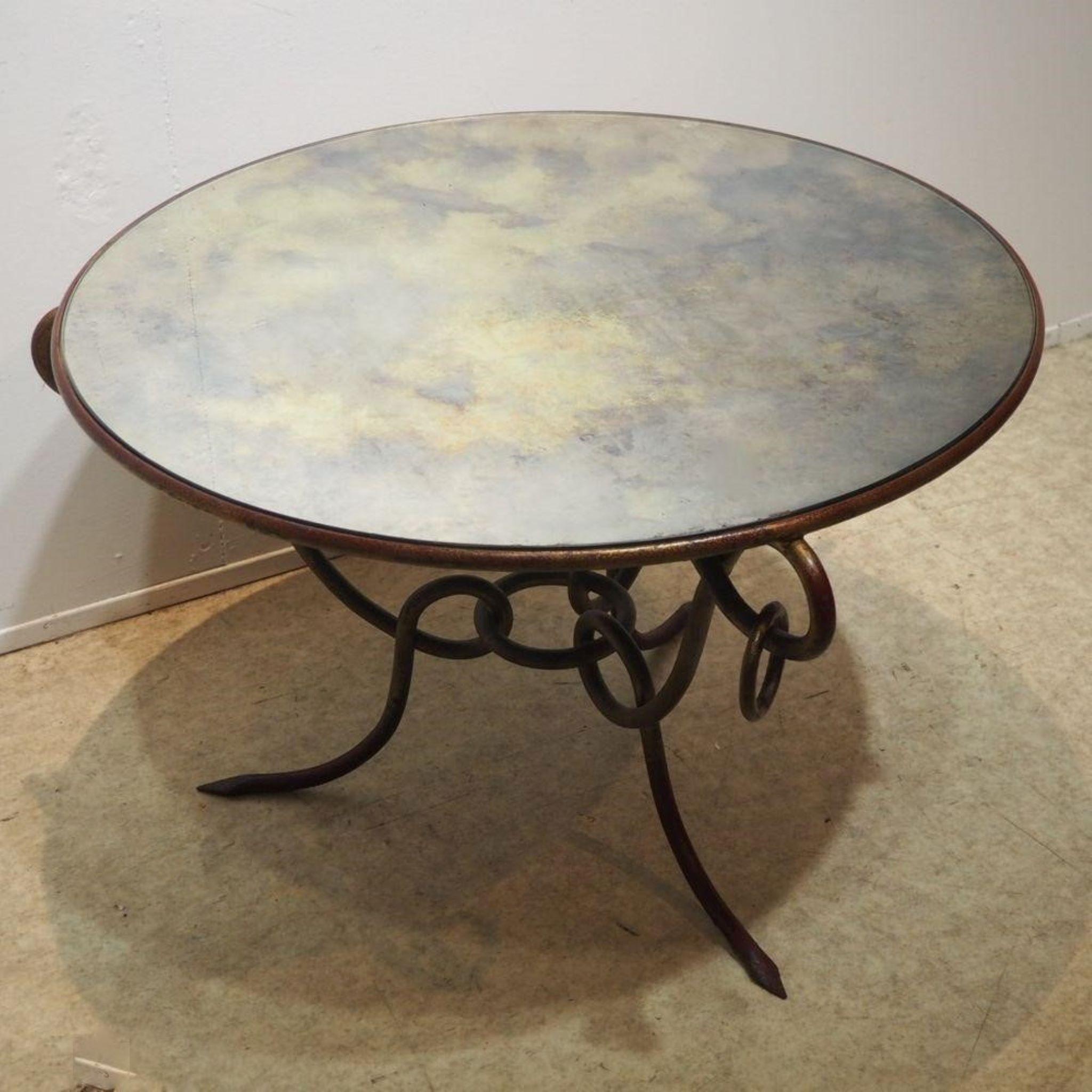 Gueridon formed by a circular beveled mirror top, set in a gilt structure with patina, rests on an interlocking tripod base in gilt iron with gilt patina, joined in the center by a ring, decorated with a free ring on each top.

France