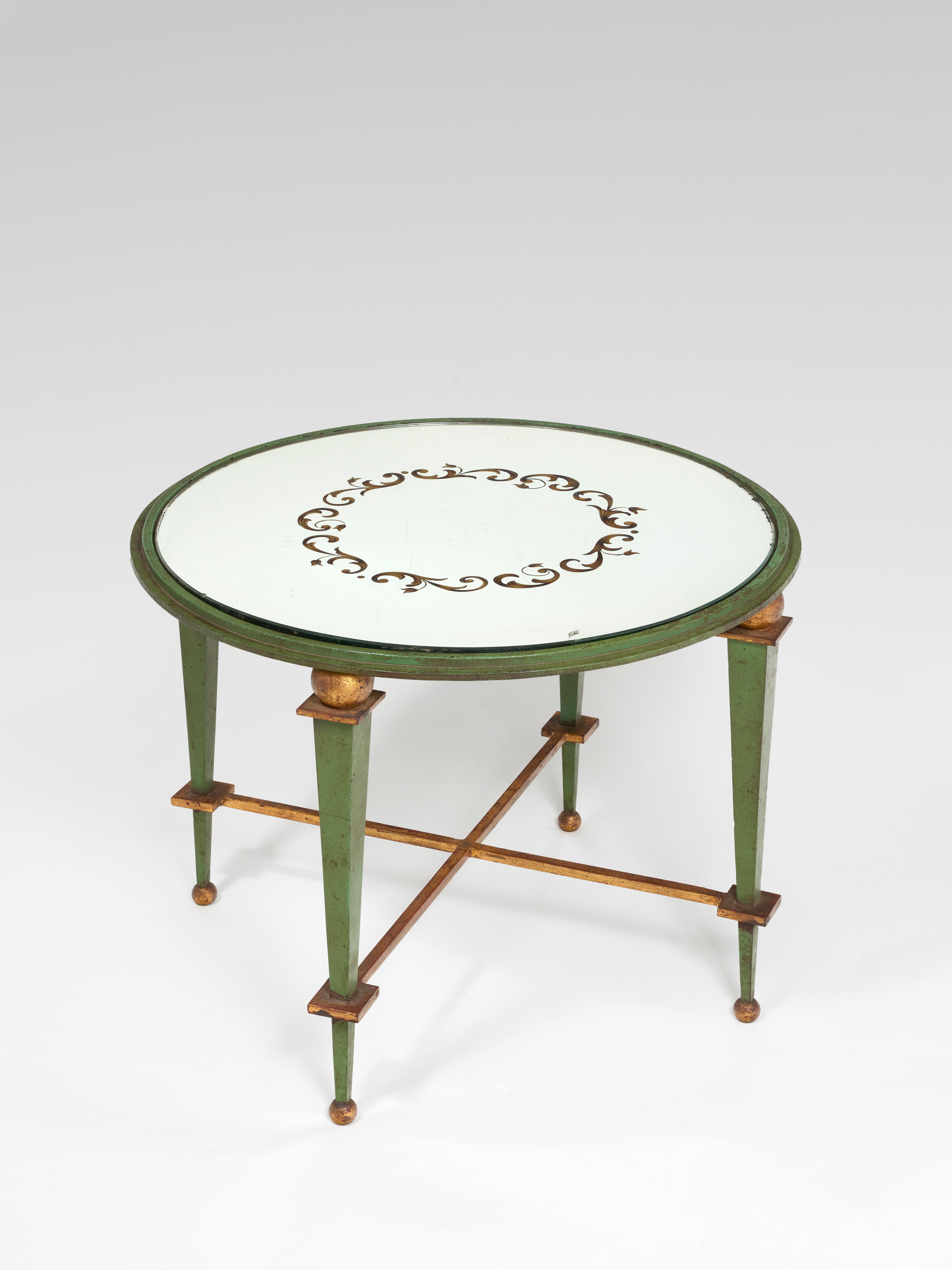 Coffee table with circular top in eglomerate glass with interlacing decoration.
Green and gold wrought iron base with four legs joined by an 