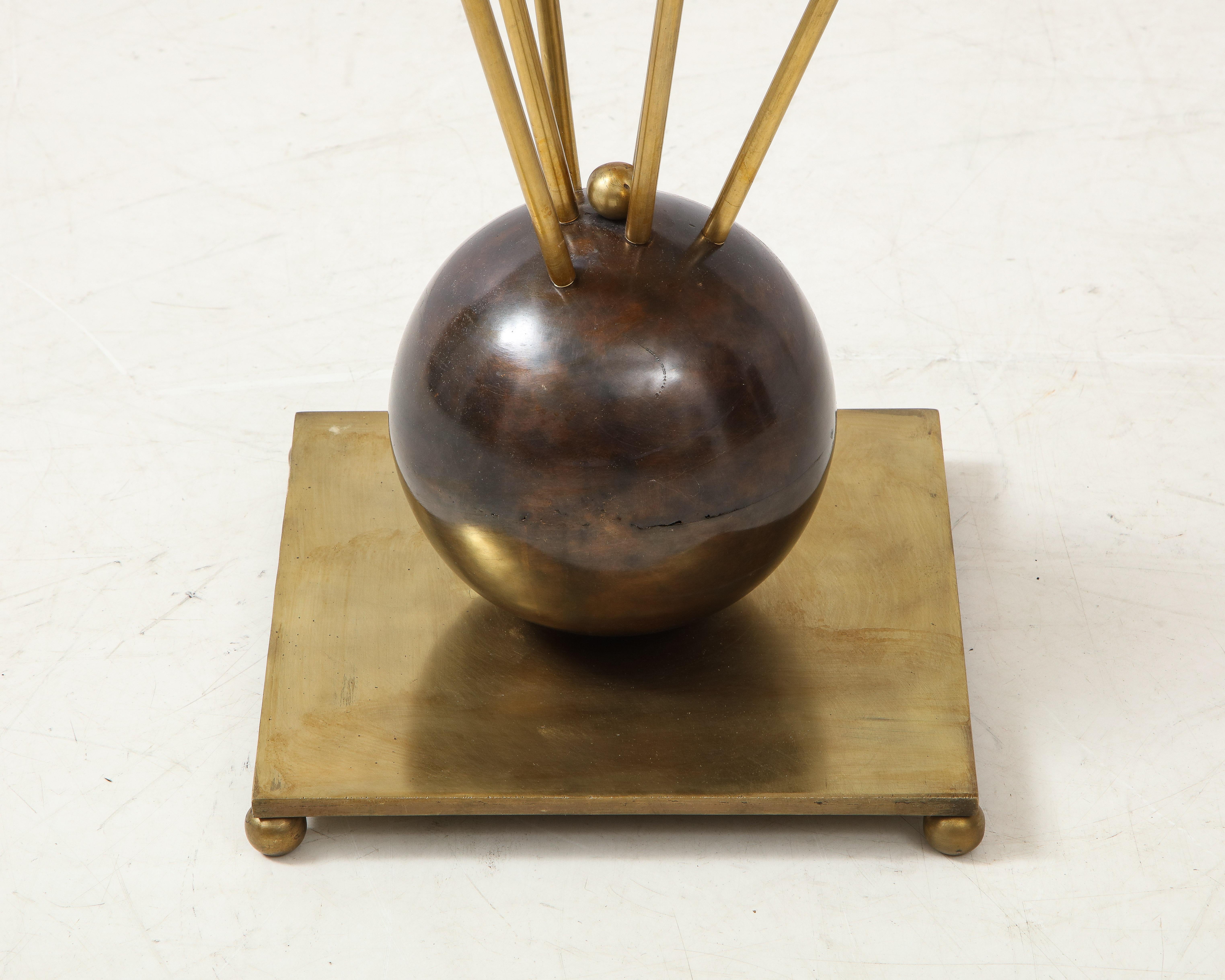 An elegant guéridon circular brass side table. Six stems extend from a central patinated bronze ball sitting on a brass plate raised on ball feet. A simple brass frame holds an opalescent glass table top.