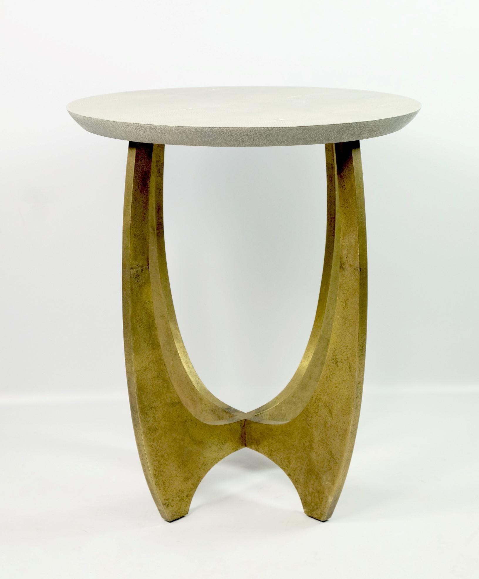 This gueridon table is made of textured brass with a round shagreen top.
The brass has been hammered by hand to give an irregular and artistic finish aspect.
The light grey color of the shagreen contrasts slightly with the brass base, which makes