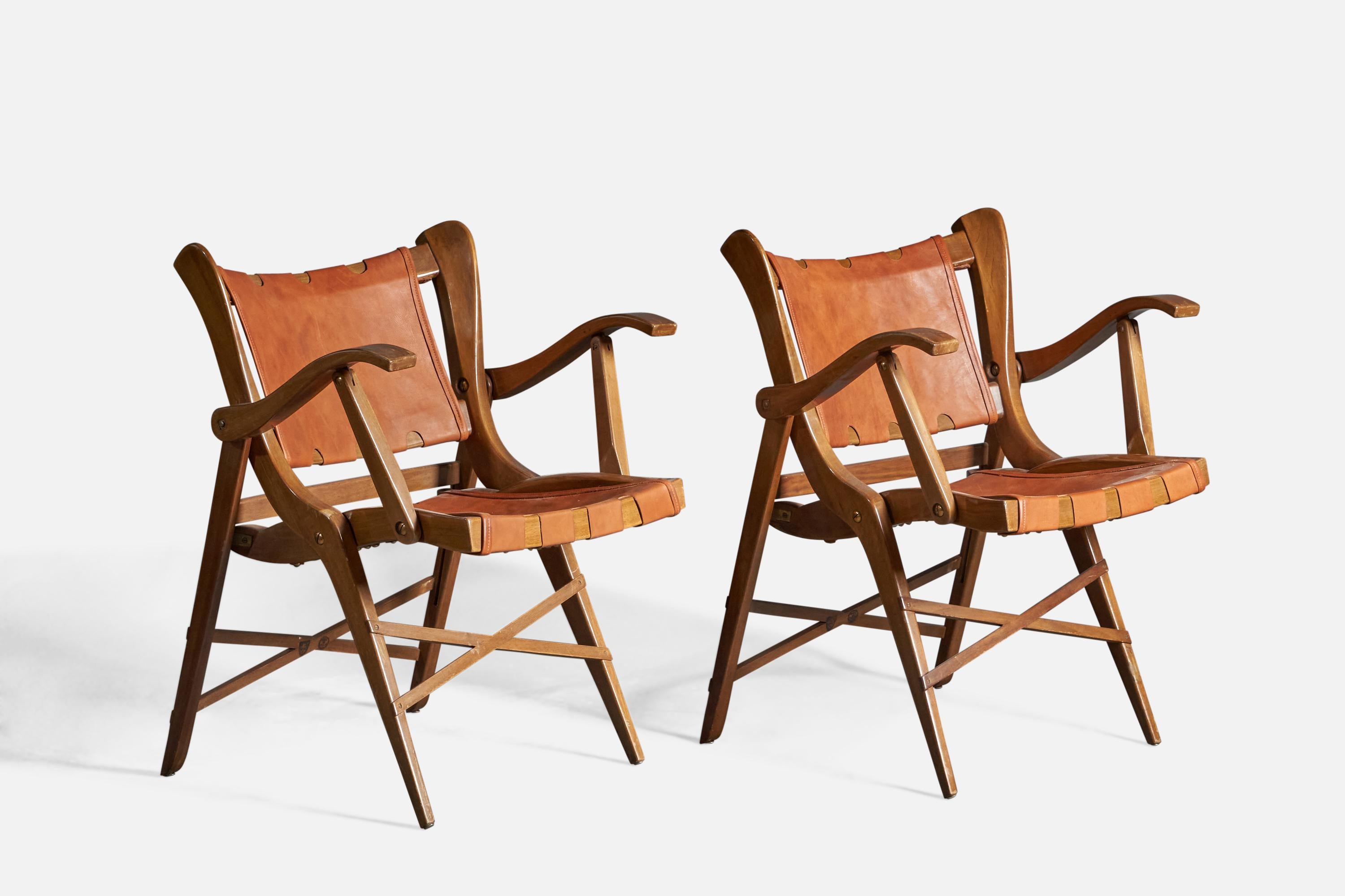 A pair of walnut and leather folding lounge chairs or side chairs, designed and produced by Guglielmo Pecorini, Italy, c. 1940s.

