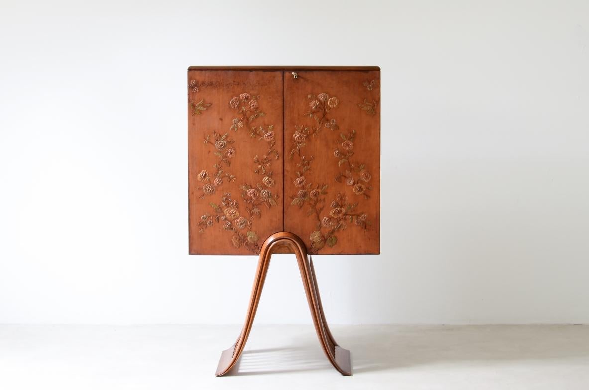 COD-2474
Guglielmo Ulrich (1904 - 1977)

Unique bar cabinet in leather painted with floral motifs and curved wooden base. Interior with mirrors, flamed maple doors with glass holder shelves and two drawers.

ARCA manufacture, 1948.

80x35x135