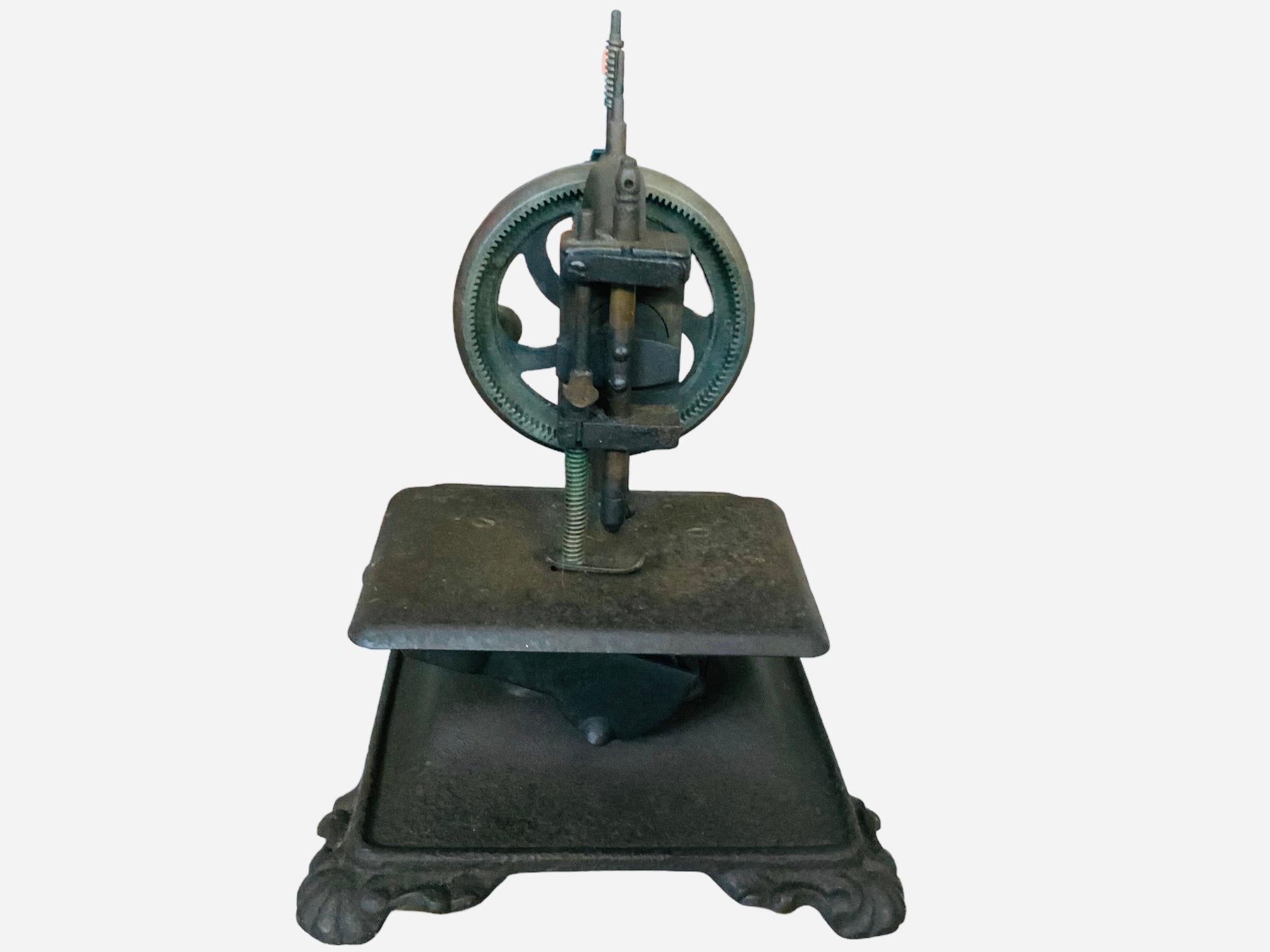 This is a Guhl & Harbeck style chainstitch hand crank sewing machine. The C shaped cast iron machine is painted black and its rectangular base with four scrolls and shells feet corner is painted the same color. The sewing machine does not work. It
