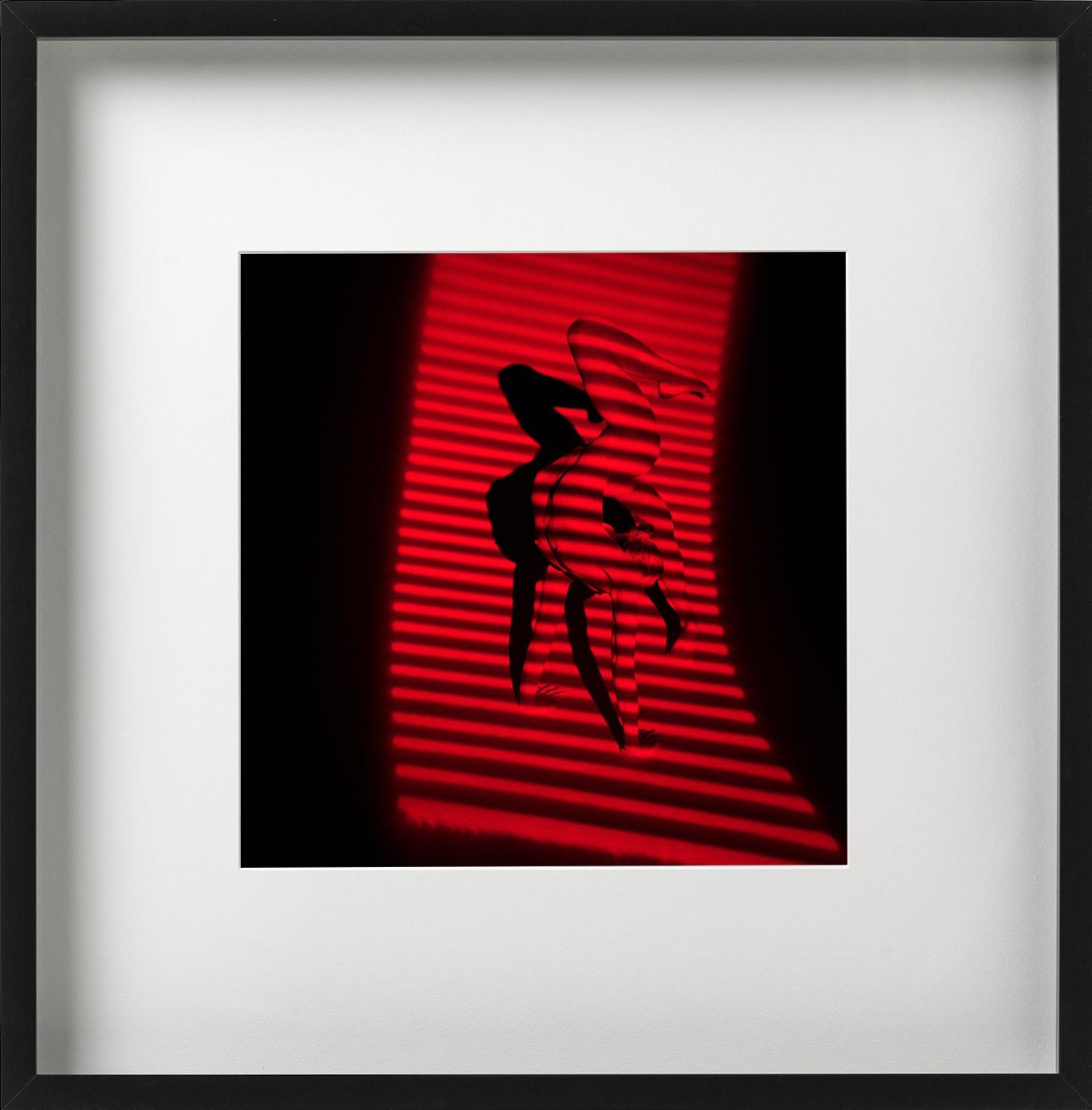 Giulia and Red Stripes - nude photograph of female model with red background - Photograph by Guido Argentini