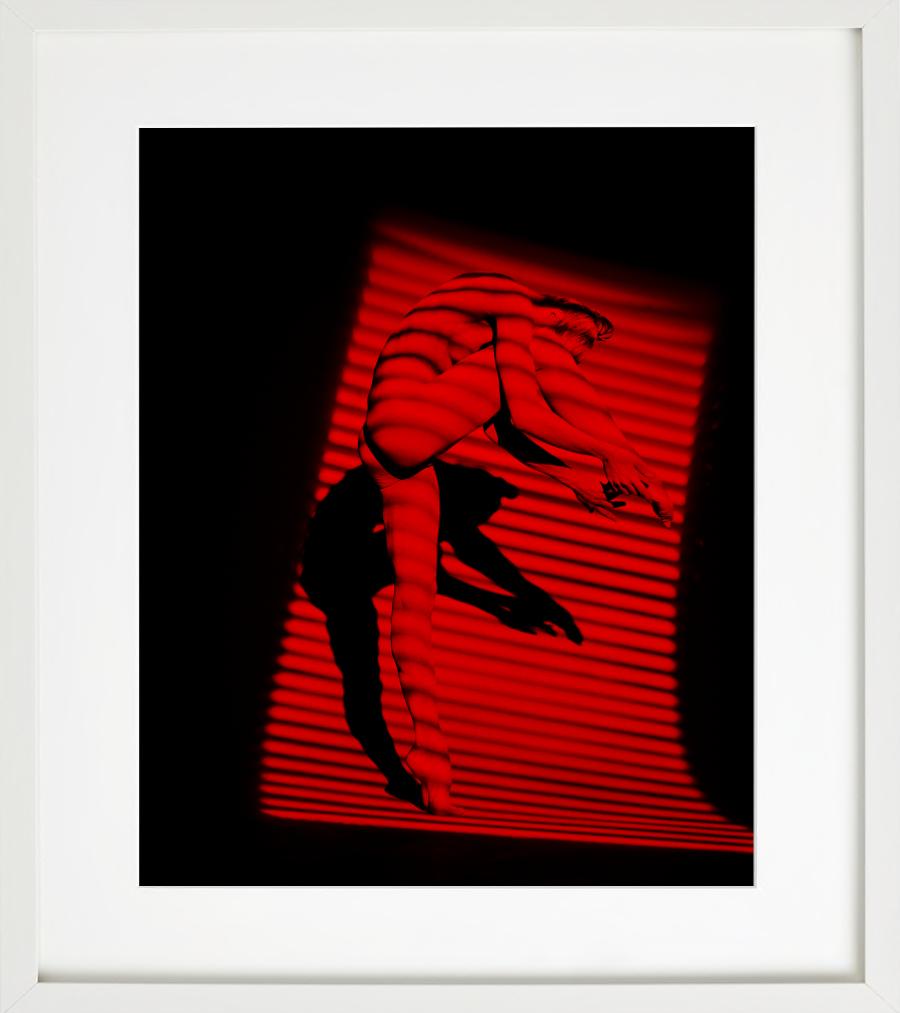 Giulia As Bird – Aktfotografie eines weiblichen Modells mit rotem Hintergrund (Schwarz), Nude Photograph, von Guido Argentini
