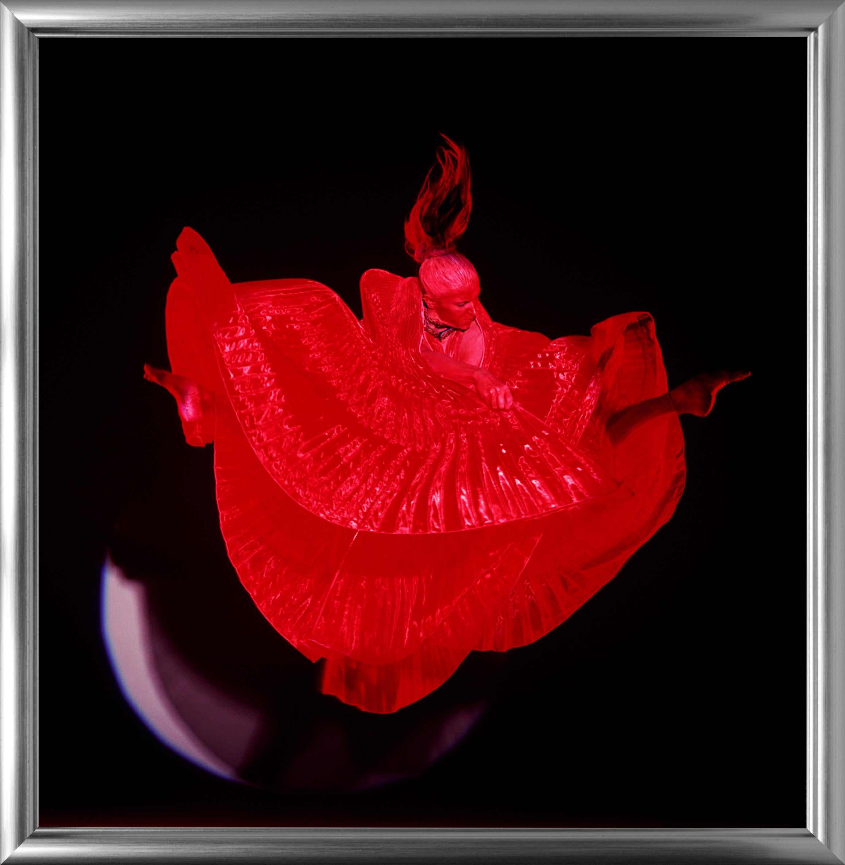 Giulia Jumping in White Circle – nacktes Foto, weibliches Model vor rotem Hintergrund (Schwarz), Figurative Photograph, von Guido Argentini