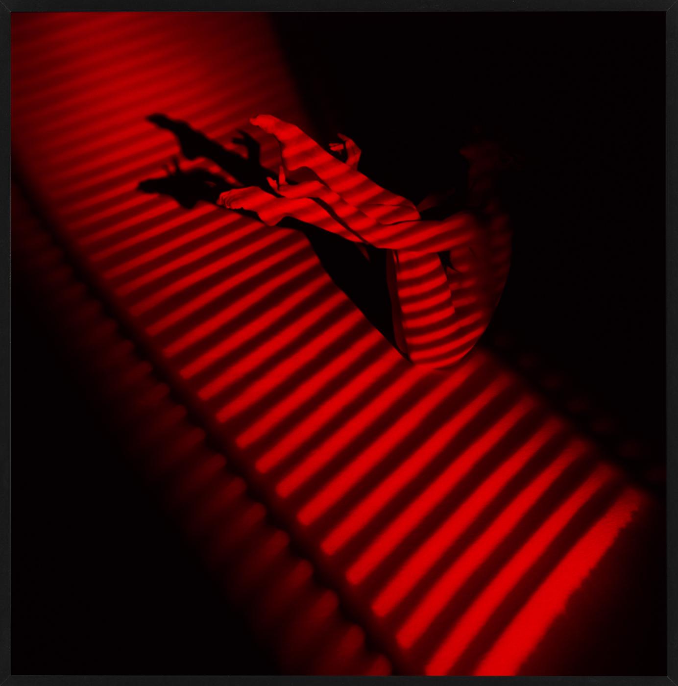 Giulia's Legs & Red Stripe - nude photograph of female model with red background - Photograph by Guido Argentini