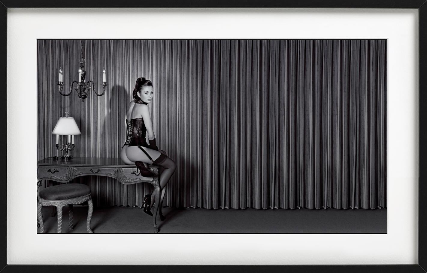 Petra in einem Lederkorsett – Modell auf antikem Schreibtisch sitzend, Kunstfotografie – Photograph von Guido Argentini