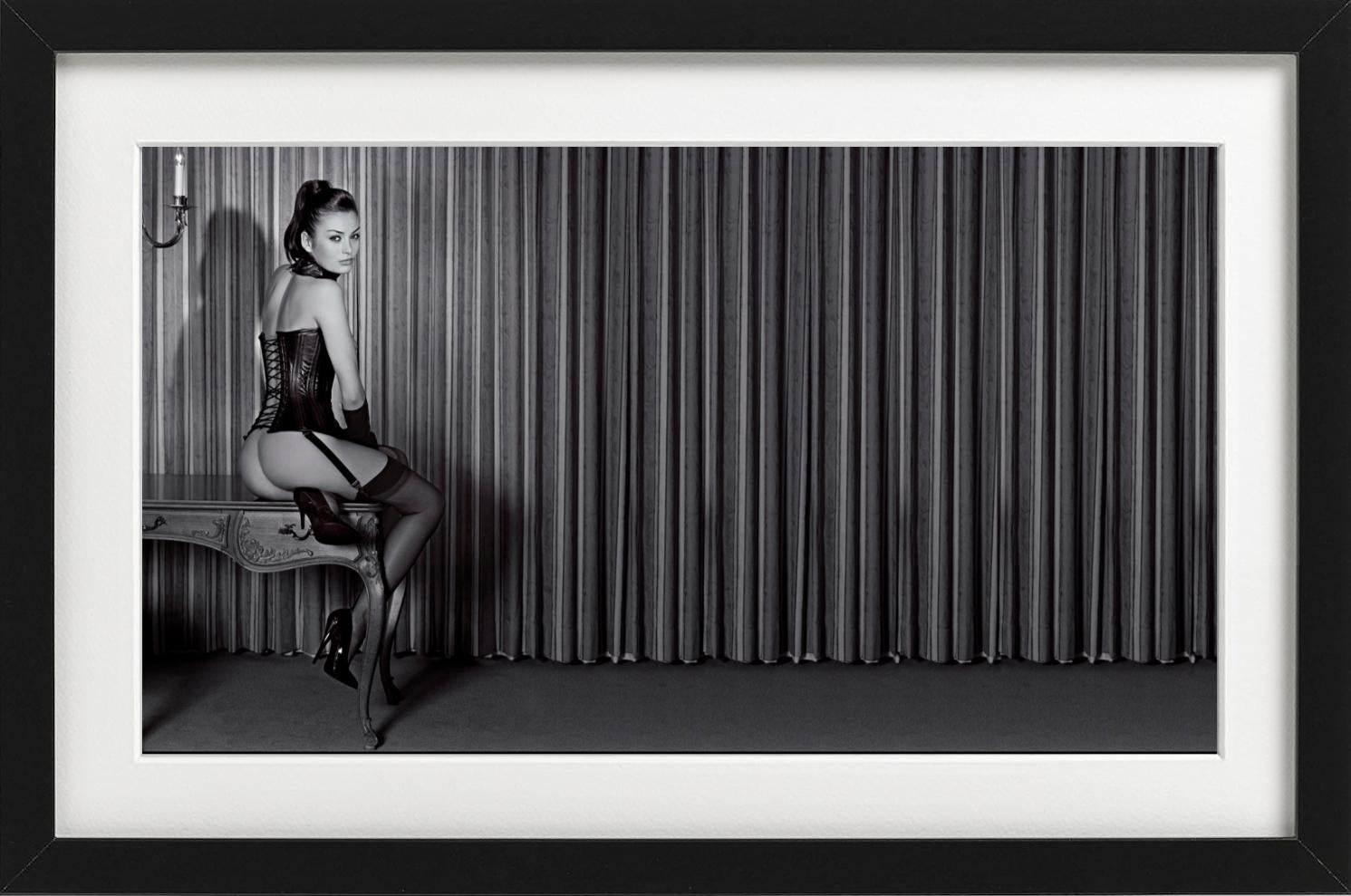 Petra in a Leather Corset - model sitting on antique desk, fine art photography - Black Nude Photograph by Guido Argentini