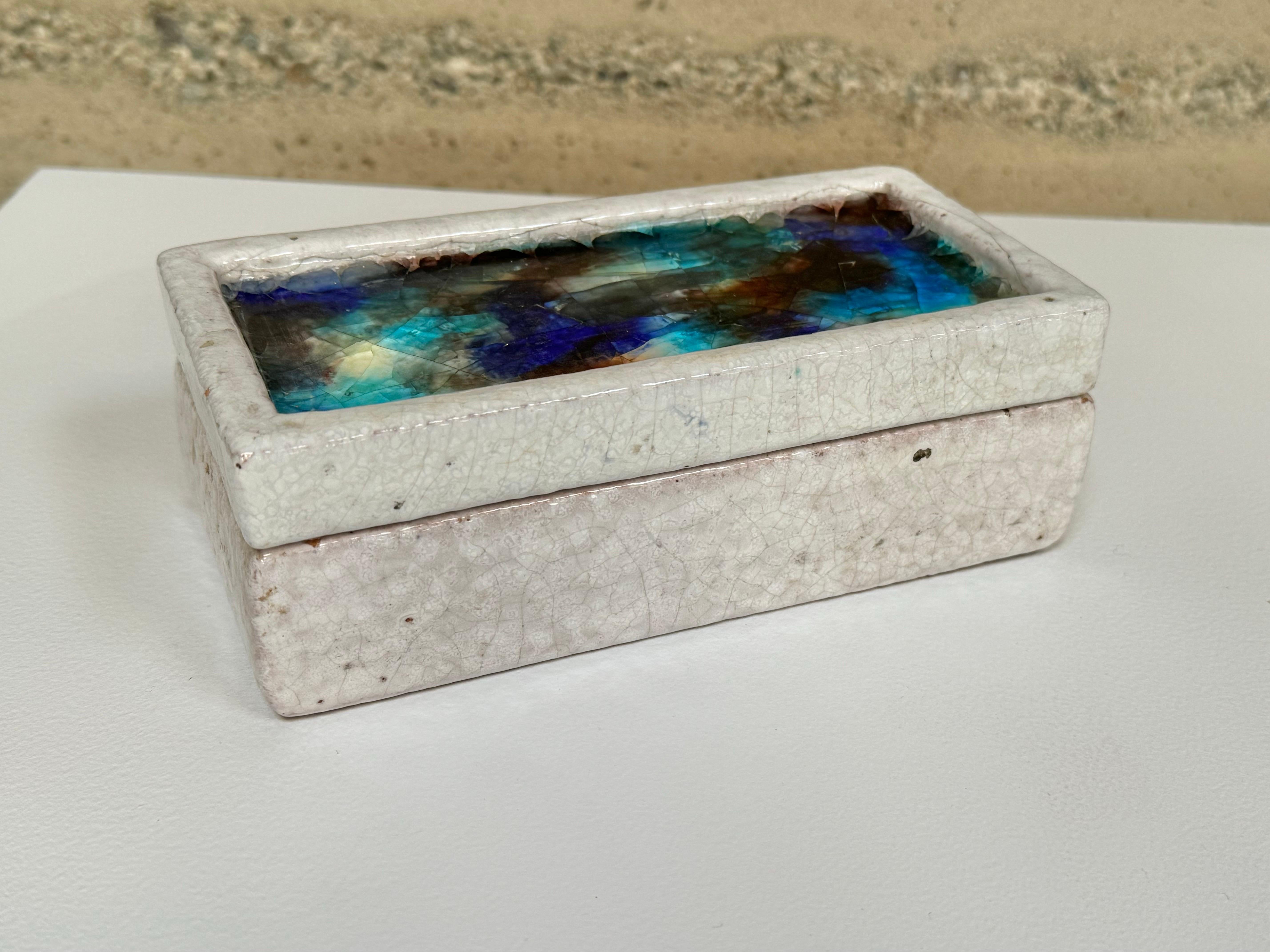 Ceramic lidded box designed by Guido Bitossi and sold by Raymor, circa 1950s. The lidded box has a colorful fused  glass top and a soft white glaze body and is labeled on the bottom. The glaze is a cracked volcanic with imperfections as part of its