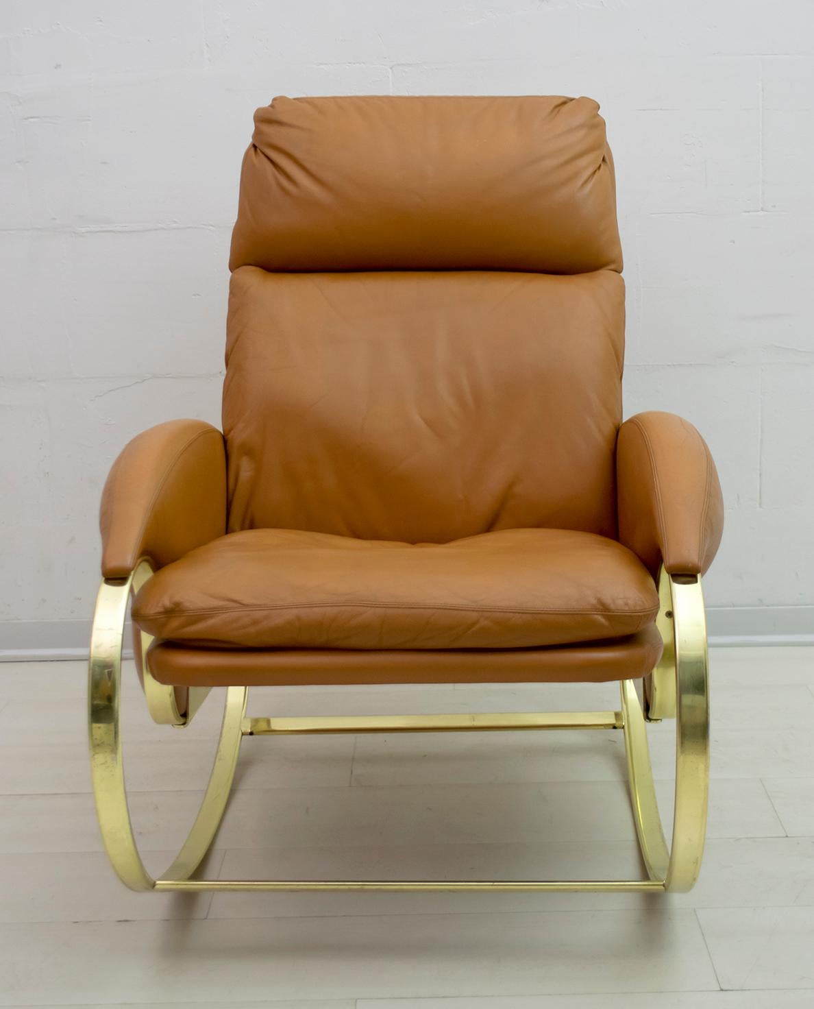 Rocking chair designed by Guido Faleschini in the 1970s. Elegant rocking chair with curved and golden metal structure, the upholstery is in real leather. As can be seen from the photos, normal signs of wear over time.