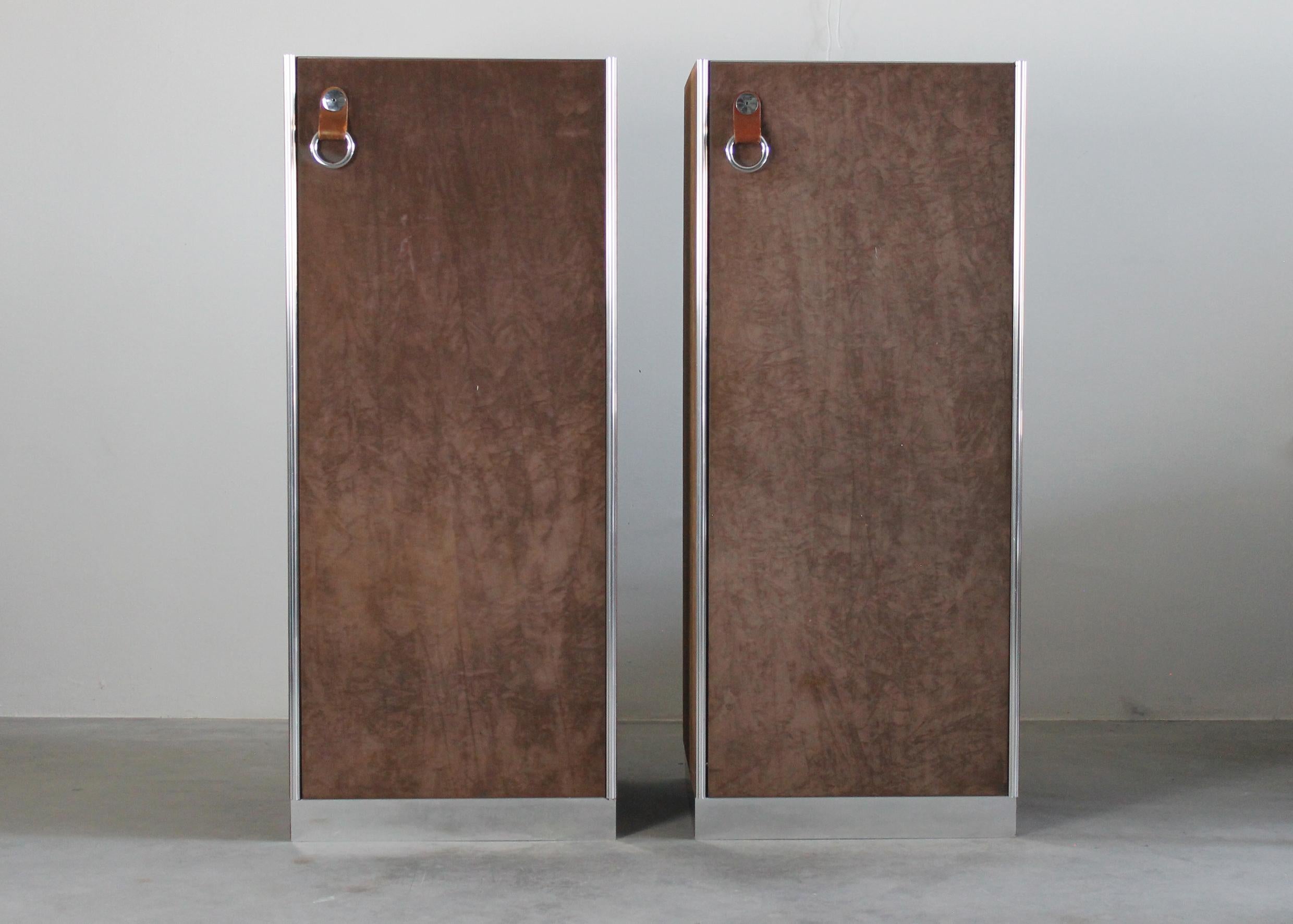 Set of two cabinets with suede clad panels, each panel is surrounded by a chromed steel frame and presents metal ring shape handles on the frontal part.

These cabinets was designed by Guido Faleschini as part of the Pace Collection for Italian