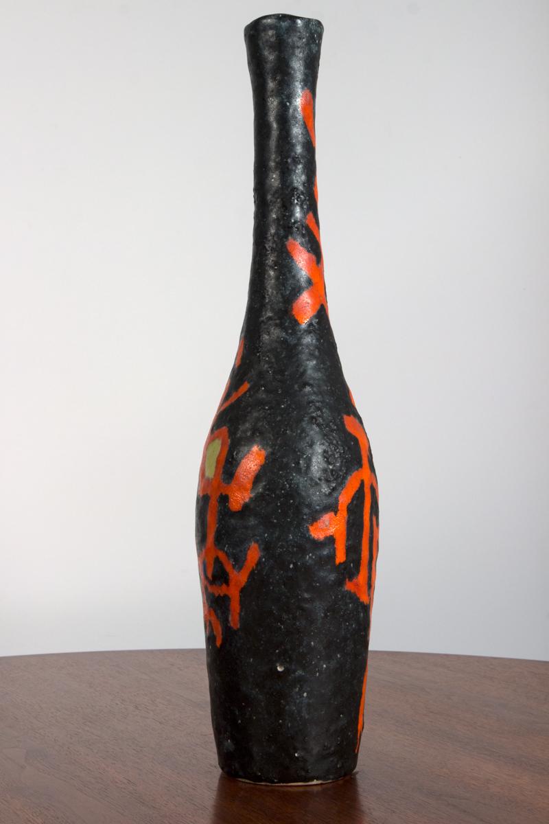 Stunning expressionist bottle vase by Guido Gambone. Freehand painted lines of coral red are accented with cobalt blue and citron yellow on black background. The matte finish of the glazed stoneware enhances the rustic texture throughout its classic