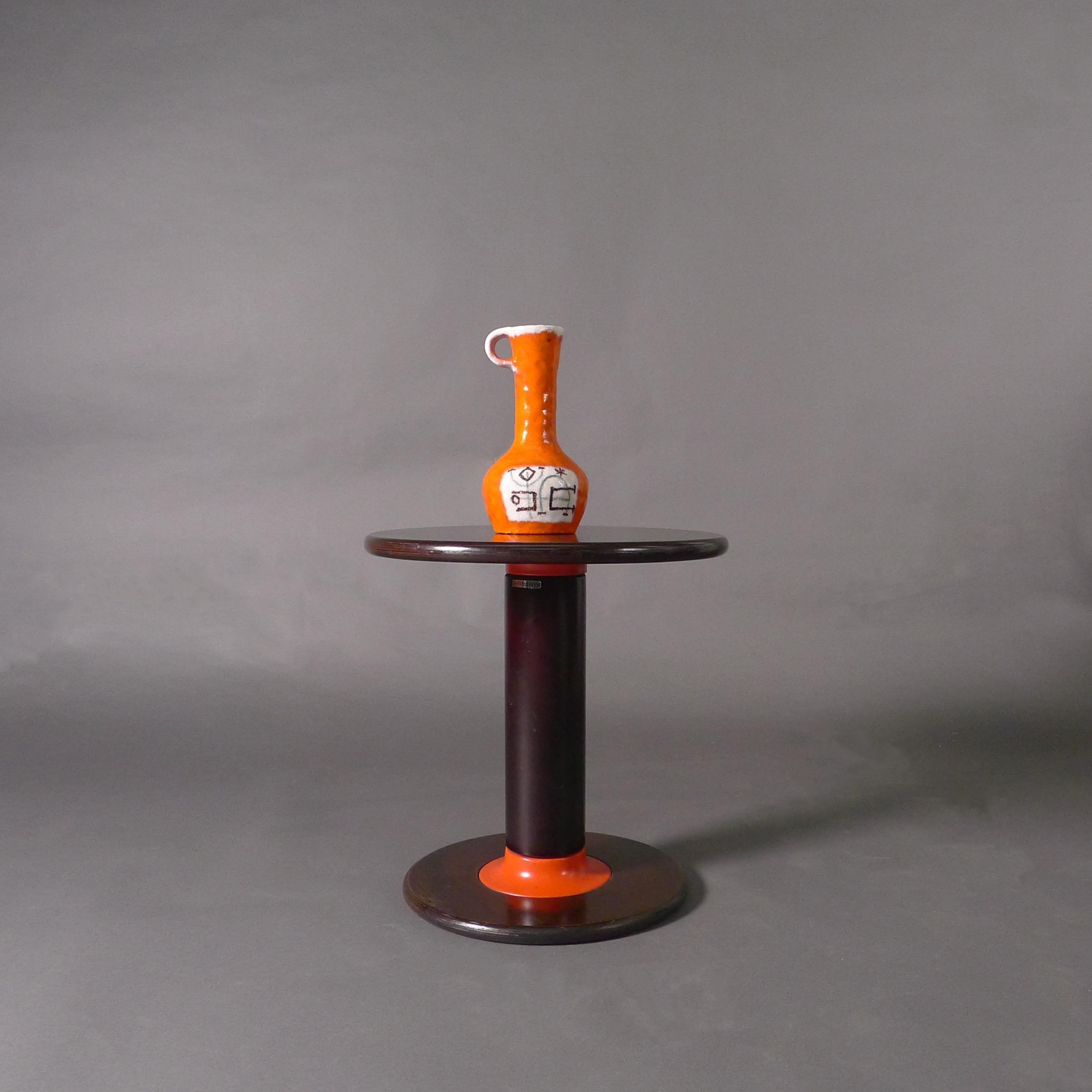 Guido Gambone (1909-1969)
Vaso in maiolica con manico a Looping
Smalto arancione con riserva ovale su ciascun lato, dipinta con simboli grafici su fondo bianco.
firmato alla base Gambone / Italia e con marchio dell'asino
24,5 cm di altezza, 14 cm di
