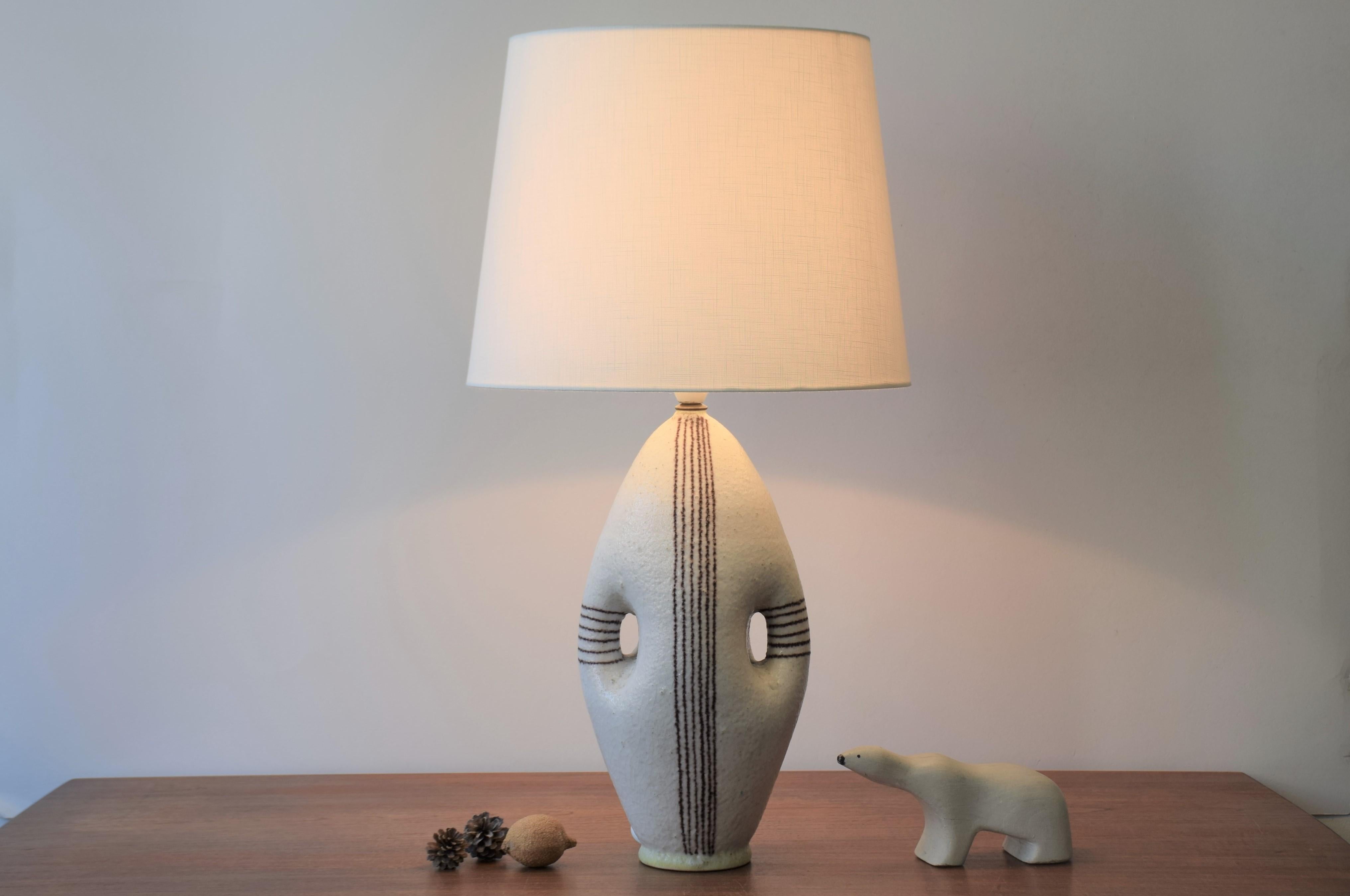 Tall table lamp by Italian ceramist Guido Gambone (1909-1969), circa 1950s.
The lamp has an anthropomorphic shape with lots of character.
The thick salt glaze is off-white with brown hand painted stripes and pale yellow rims at top and