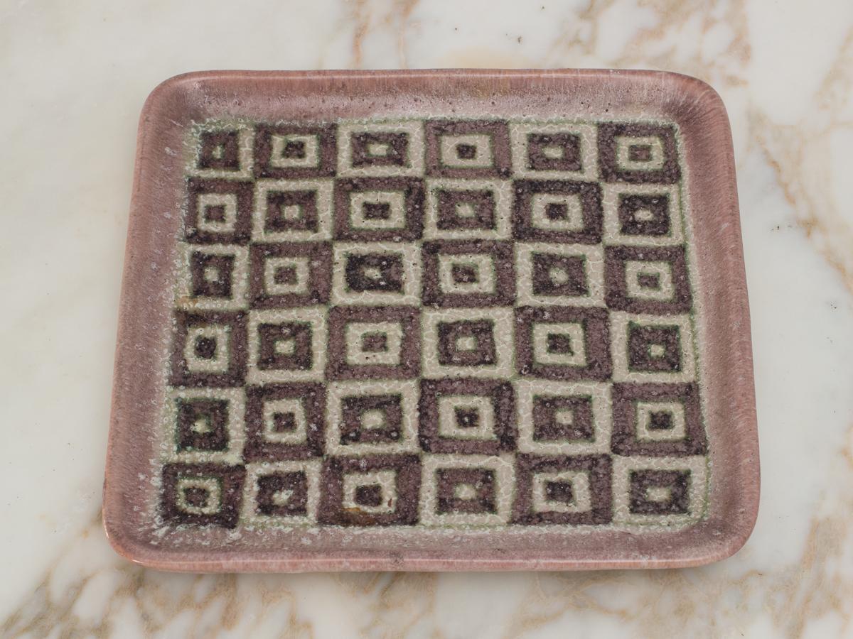 Glazed stoneware tray or platter with abstract geometric pattern, made by the Italian ceramicist Guido Gambone. Hand-built form with organic edges is covered in a dense, textured glaze that is porous and rough. Decorated with a modernist pattern of