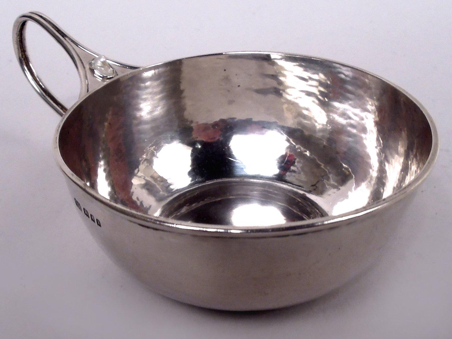 Porcionador inglés Arts & Crafts de plata de ley, 1925. Cuenco curvo y redondo con asa de lazo alargada con montura partida; la montura superior tiene nácar irregular. Martilleo manual visible.
El clásico diseño Ashbee de George Henry Hart, que