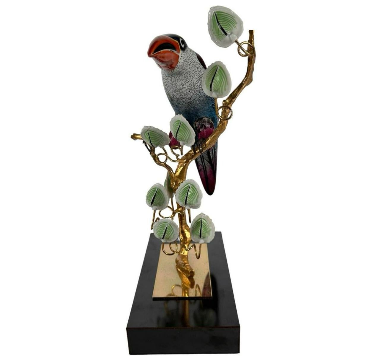 An Italian ceramic  toucan sculpture on a gilt bronze and tole metal wire tree branch by famed Italian artist Giulia Mangani. The colorful bird is accented by hand painted ceramic leaves. Mounted on a rectangular resin plinth. Makers label Mangiani