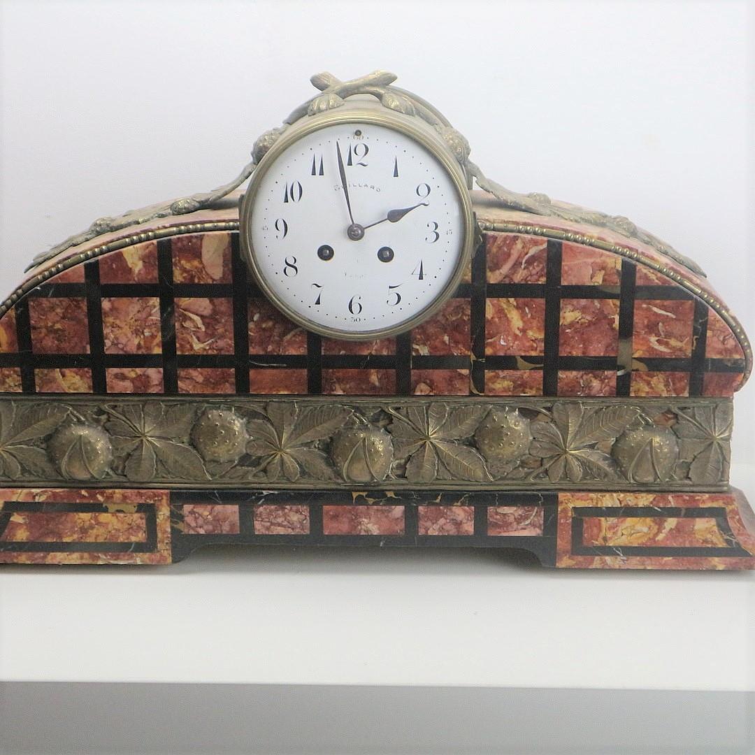 Guillard marble mantel clock with brass applications showing chestnut leaves and nuts, with pendulum, width: 54 cm, height: 32 cm.
With two Art Deco marble side plates, with bronze mountings, height: 23.5 cm and 21.5 cm.
In good condition for its