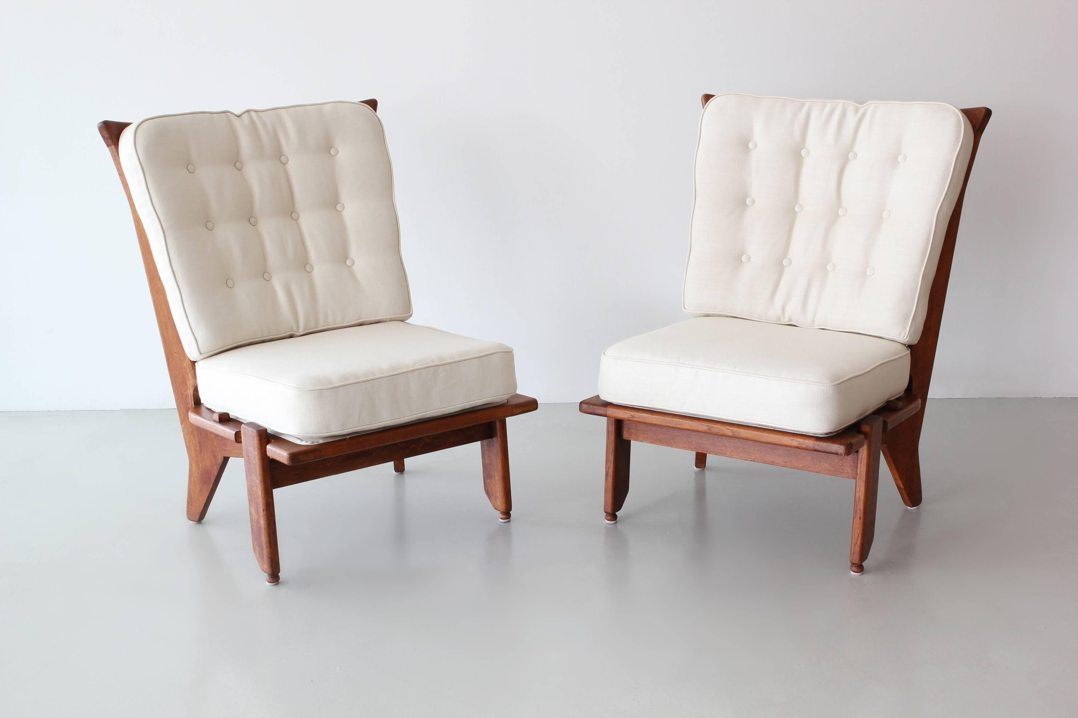 Pair of lounge chairs by Guillerme and Chambron.
Oak chairs with signature spindle back and great angled legged profile. 
Newly upholstered in linen.