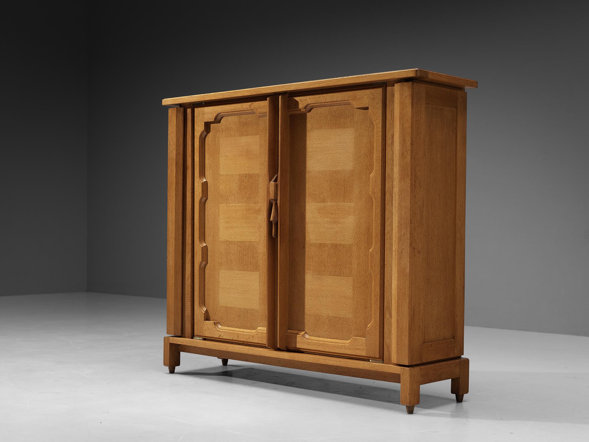 Guillerme et Chambron for Votre Maison, 'Bouvine' cabinet, oak, France, 1960s

This case piece is designed by Guillerme and Chambron and features two large doors, both with framed oak inlays around the edges. Down the centre there is a lever that is