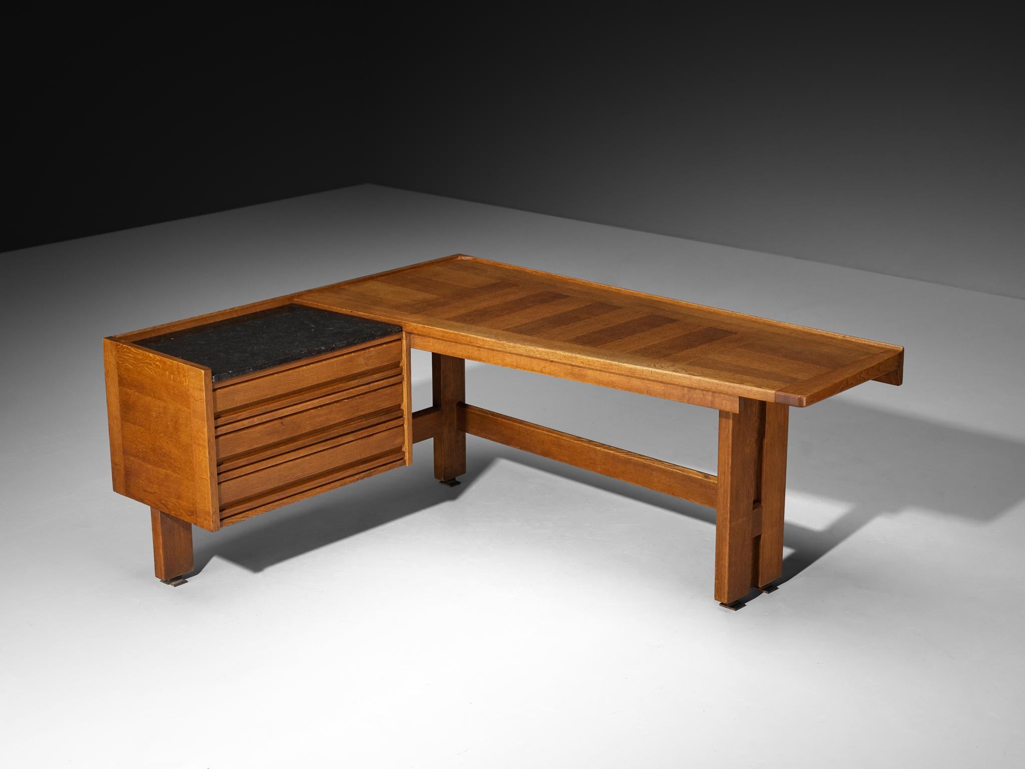 Guillerme et Chambron for Votre Maison, corner writing desk, oak, stone, France, 1960s

A design by Guillerme et Chambron, featuring a corner desk crafted primarily from oak. The desk's angular design features a L-shaped structure with two distinct
