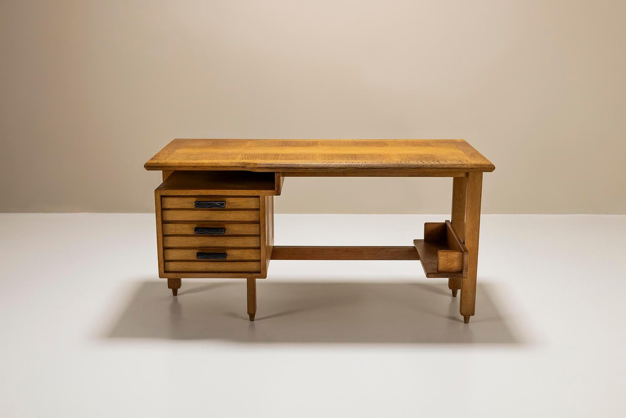 Este escritorio Guillerme & Chambron, fabricado en la década de 1960, es un bello ejemplo del diseño francés de mediados de siglo. Está hecho de madera de roble de alta calidad, lo que garantiza una construcción robusta y duradera. Los diseñadores,