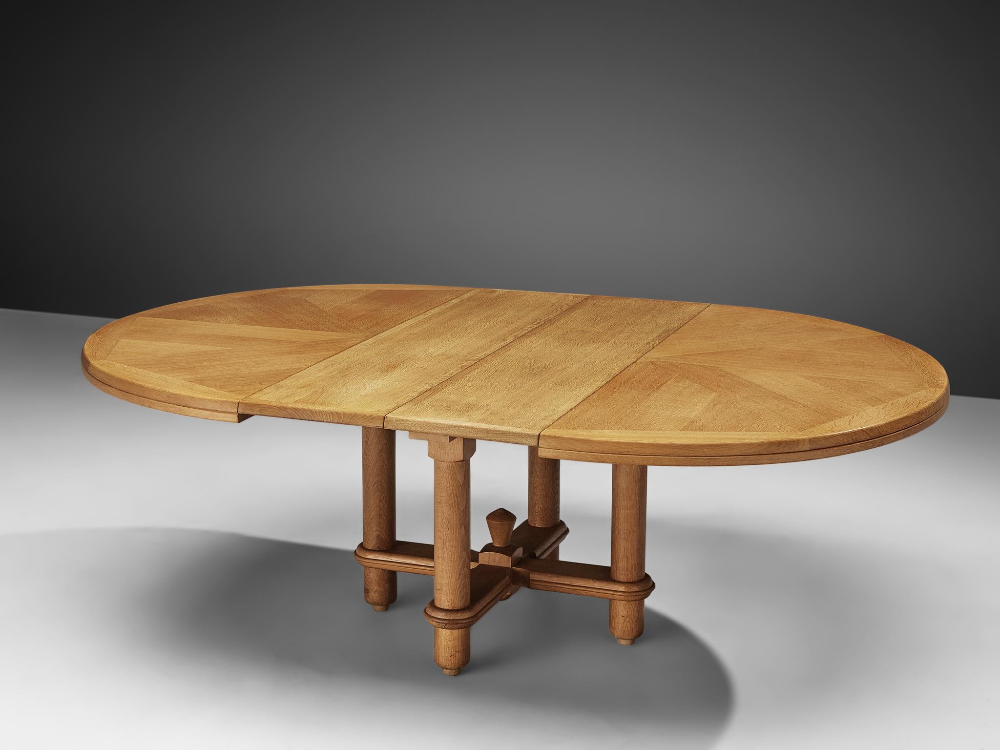 Guillerme et Chambron, extendable dining table, oak, 1960s.

Round shaped dining table with inlayed top. This extendable table in solid oak comes with two optional leaves, which makes it a very versatile item. The sculptural four legged base has