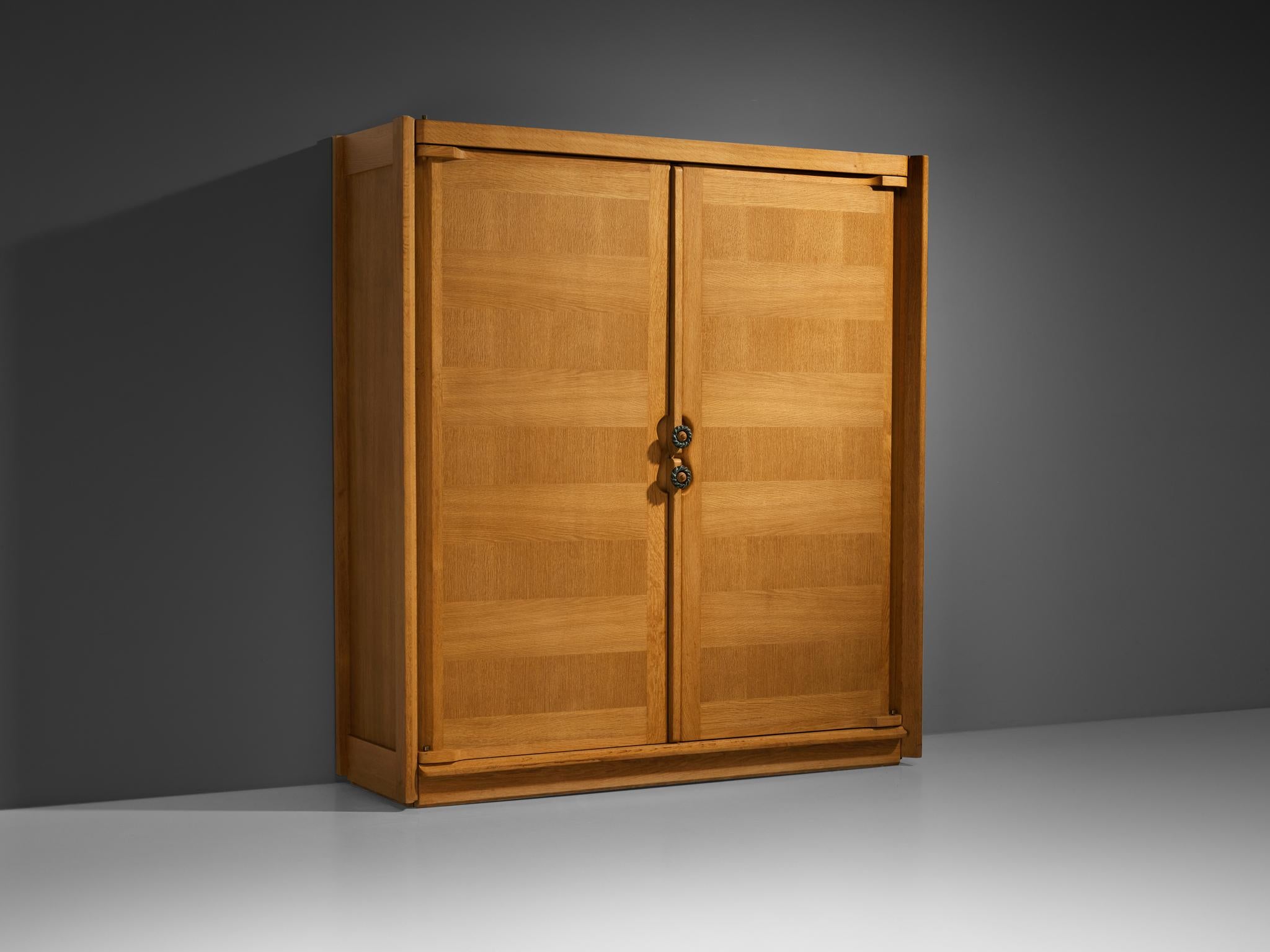 Guillerme et Chambron for Votre Maison, armoire, oak, ceramic, France, 1960s. 

This case piece is designed by Guillerme and Chambron and features geometric oak inlays, which is characteristic for the French duo. The wardrobe is equipped with blue