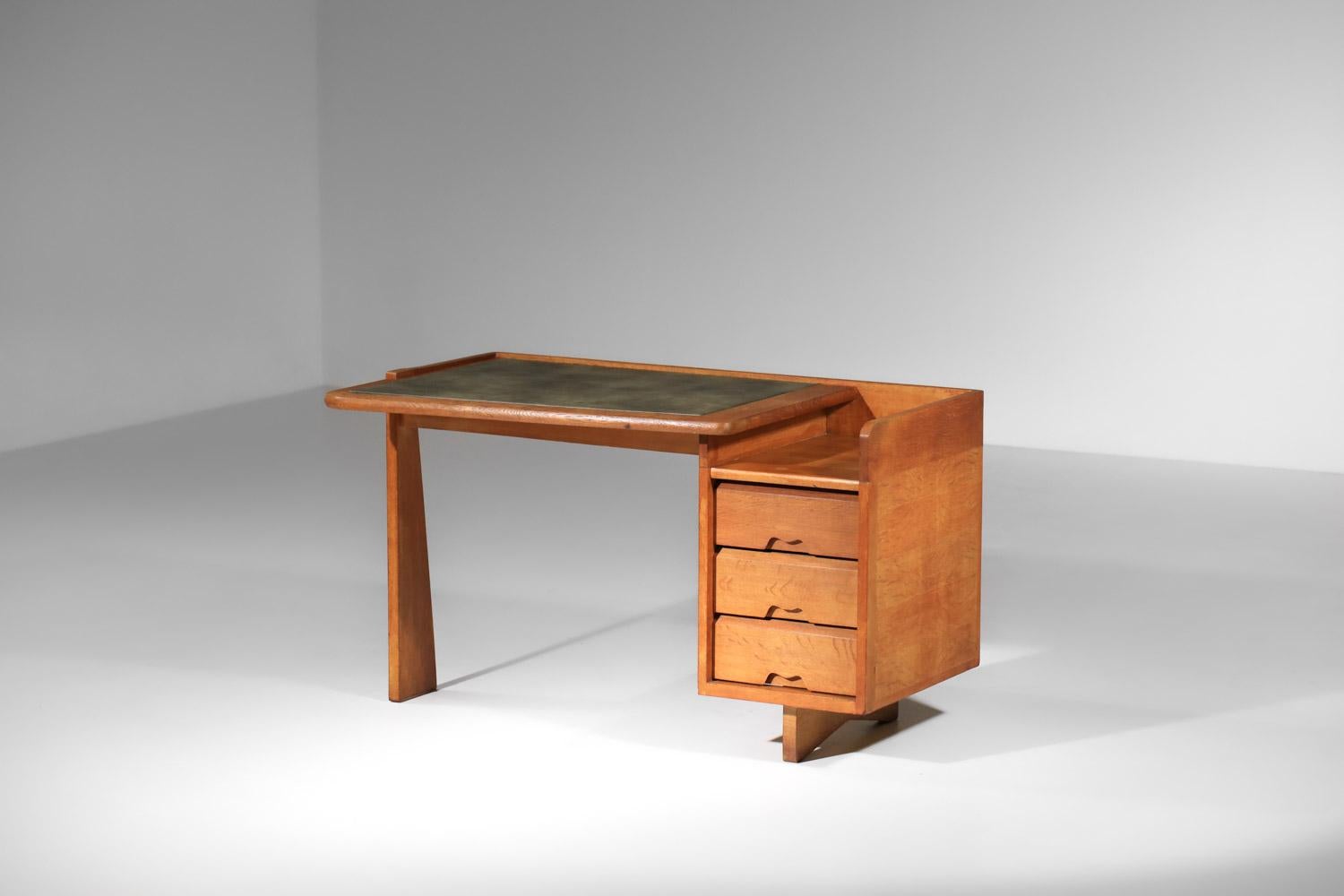 Modernist 60's desk by the famous French design duo Guillerme & Chambron for Votre Maison. This solid oak desk features a column of three drawers and a top covered with a khaki leather underside (refurbished and patinated). Sober, elegant design