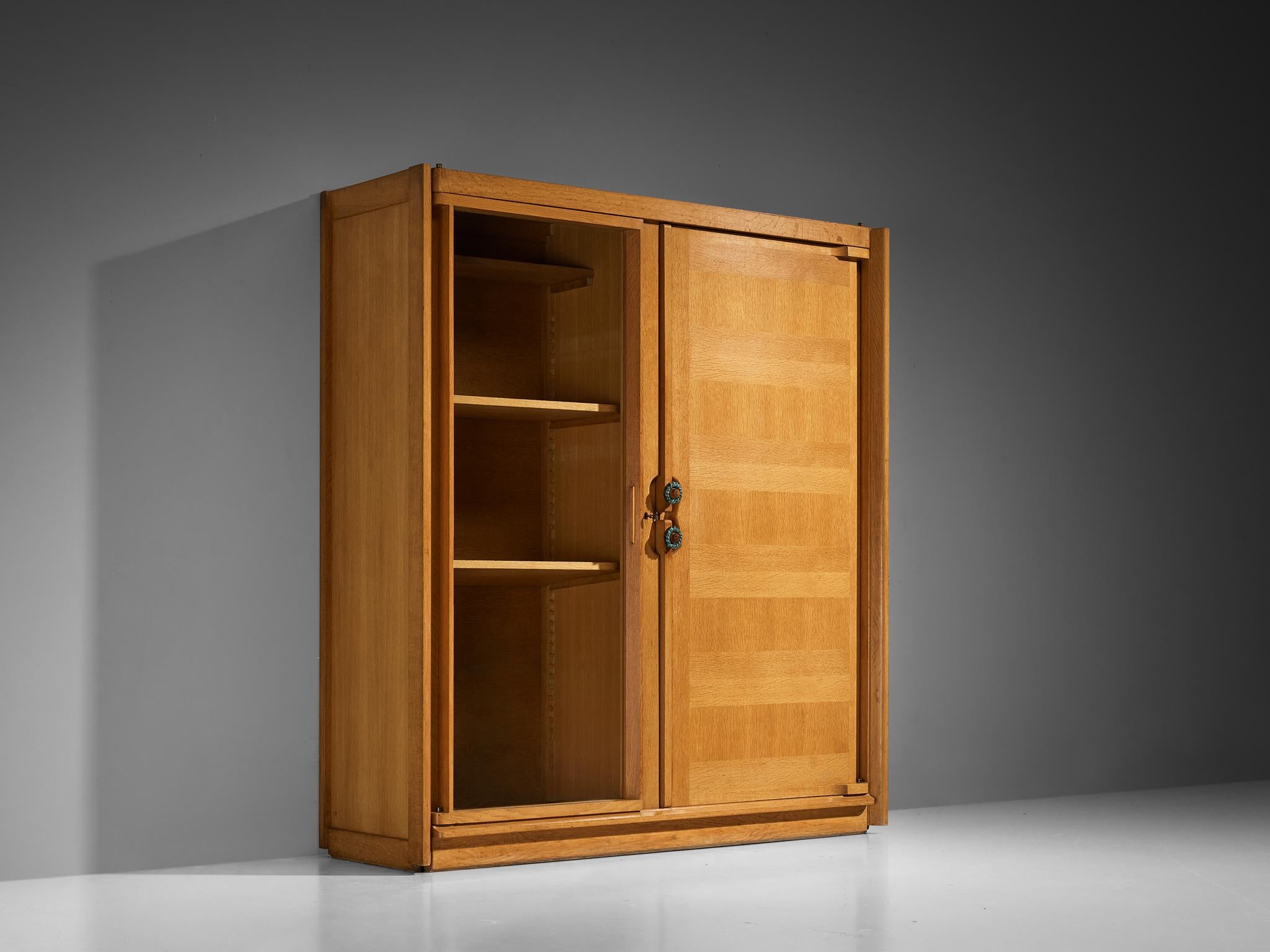 Guillerme et Chambron, highboard/cabinet/wardrobe, oak, glass, ceramic, France, 1960s

This large cabinet is based on a well-designed structure where aesthetics and functionally go hand in hand. The door panels display the typical design