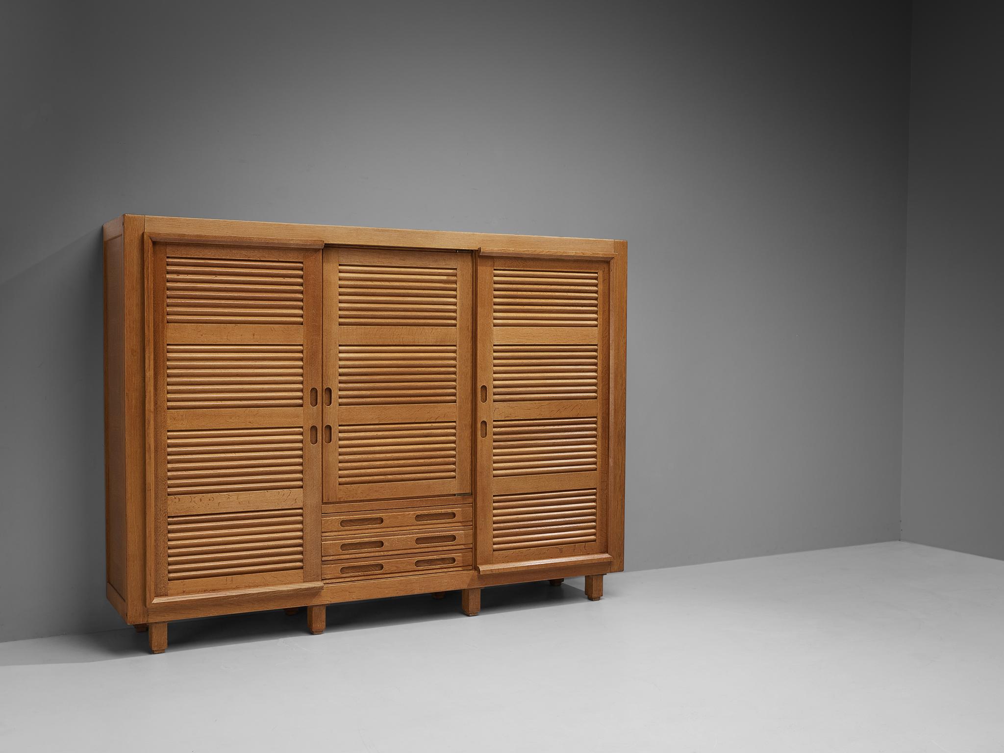 Guillerme et Chambron for Votre Maison, wardrobe, oak, France, 1960s.

This grandiose armoire is a good example of excellent woodwork by virtue of the well-designed construction based on innovative wood joints and geometric shapes that create a