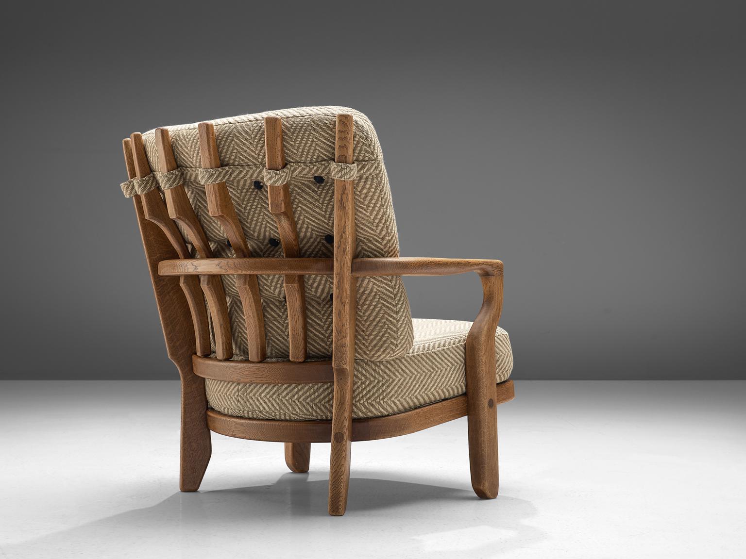 Guillerme et Chambron, lounge chair, oak and beige upholstery, France, 1960s. 

This distinctive chair in light patinated oak is by the French designer duo Jacques Chambron (1914-2001) and Robert Guillerme (1913-1990). This lounge chair in solid