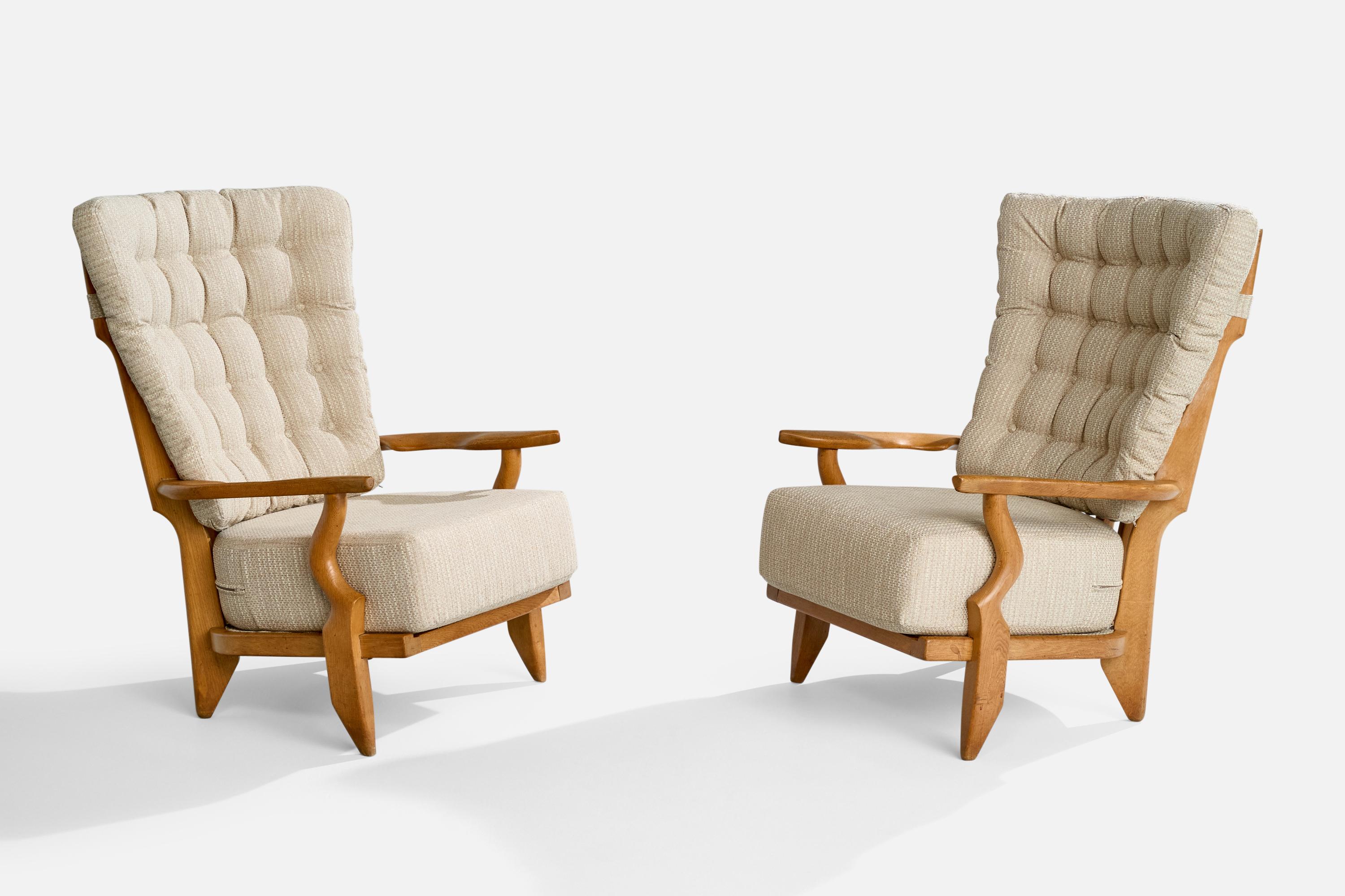 A pair of beige fabric and oak lounge chairs designed by Robert Guillerme and Jacques Chambron, France, 1950s.

Dimensions: 43” H x 30.5” W x 36”

Seat Height: 19”