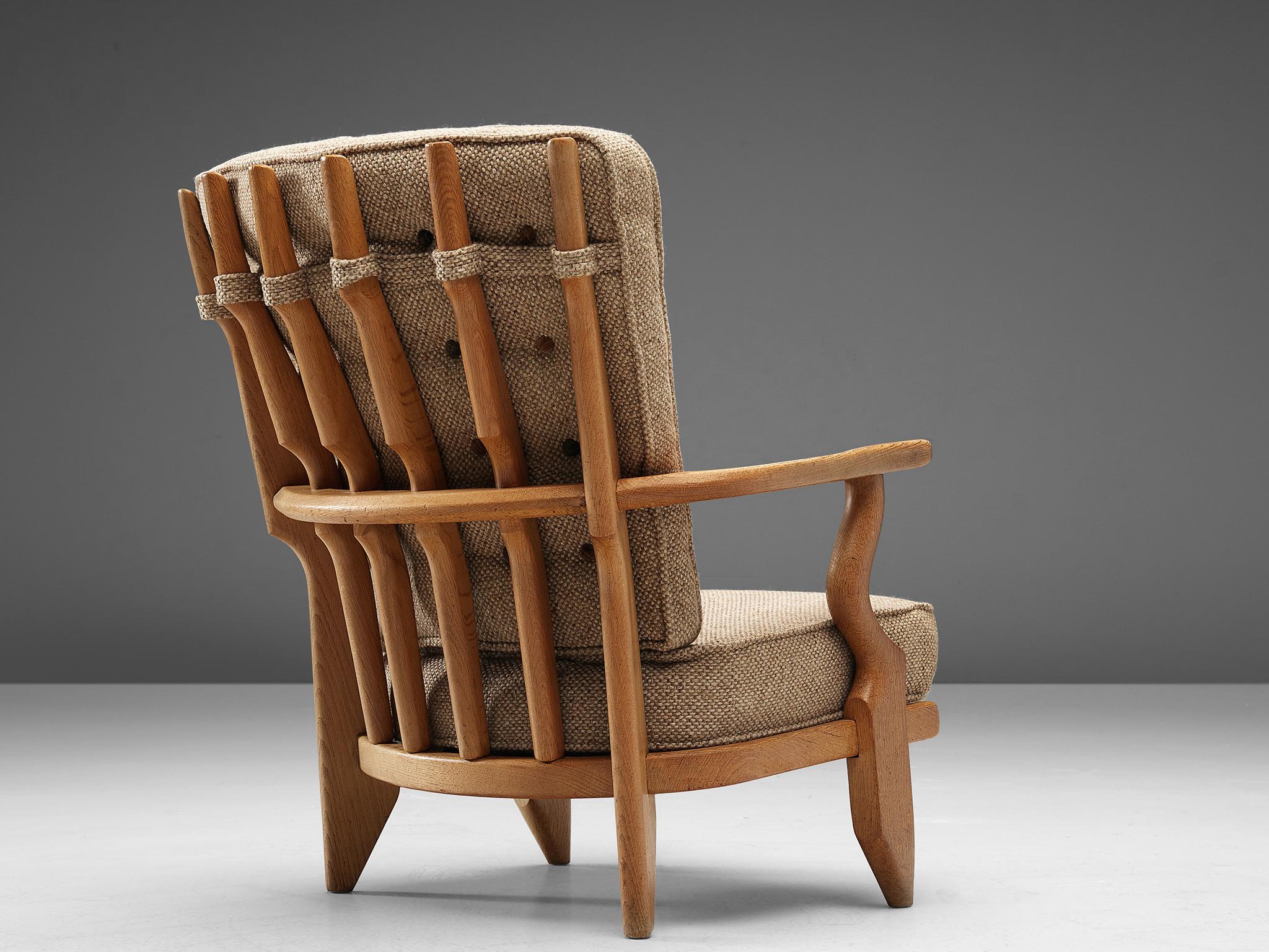 Guillerme et Chambron, lounge chair, oak and beige upholstery, France, 1960s.

Well sculpted Guillerme and Chambron 'Mid Repos' lounge chair, in solid oak with the typical characteristic decorative details at the back and capricious forms of the