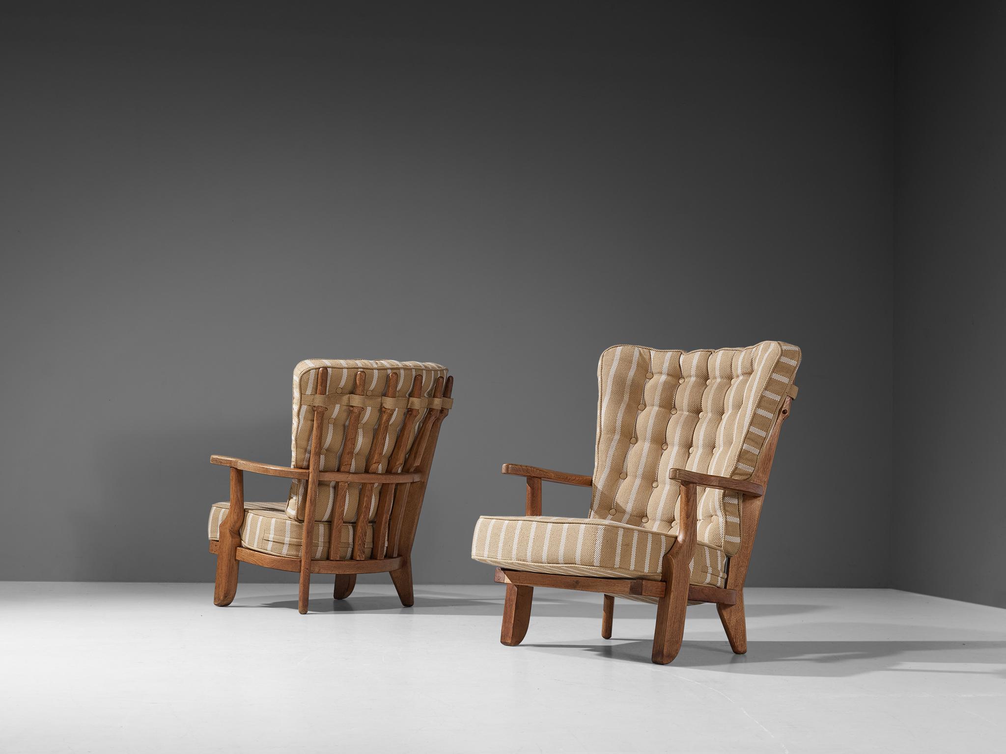Guillerme et Chambron, lounge chairs, oak and striped fabric upholstery, France, 1960s.

Well sculpted Guillerme and Chambron 'Mid Repos' lounge chairs in solid oak with the typical characteristic decorative details at the back and capricious