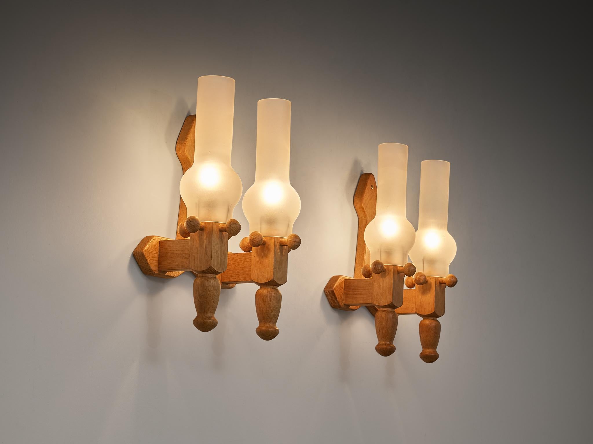 Guillerme et Chambron for Votre Maison, pair of wall lights, oak, glass, 1970s

Charming pair of wall lights, designed by designers Guillerme and Chambron in the 1970s. These lights are executed in glass and oak wood, and have a pretty substantial